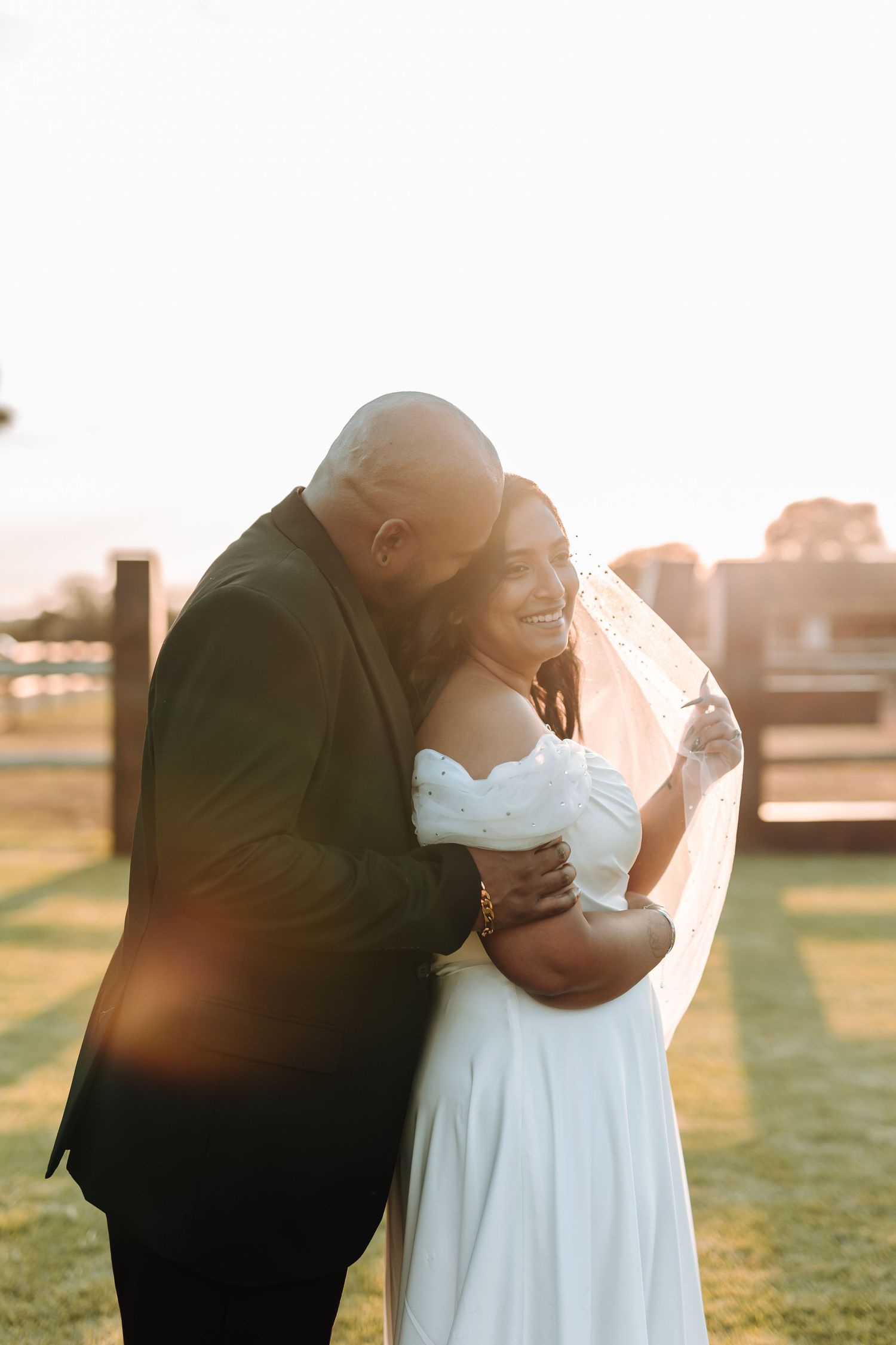A romantic sunset wedding photo of a couple embracing in formal attire.
