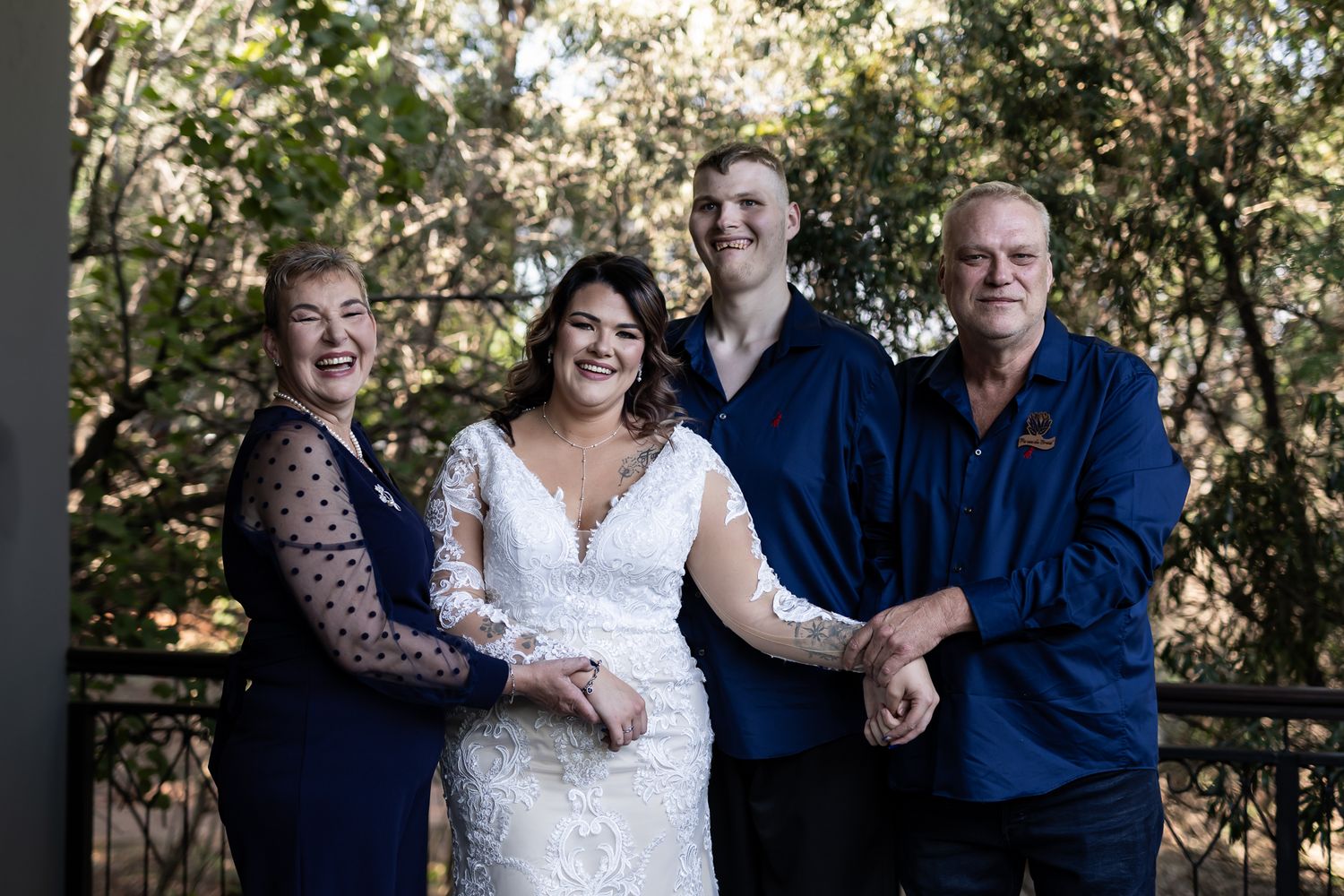 Wedding party members pose together on outdoor deck for formal portrait.