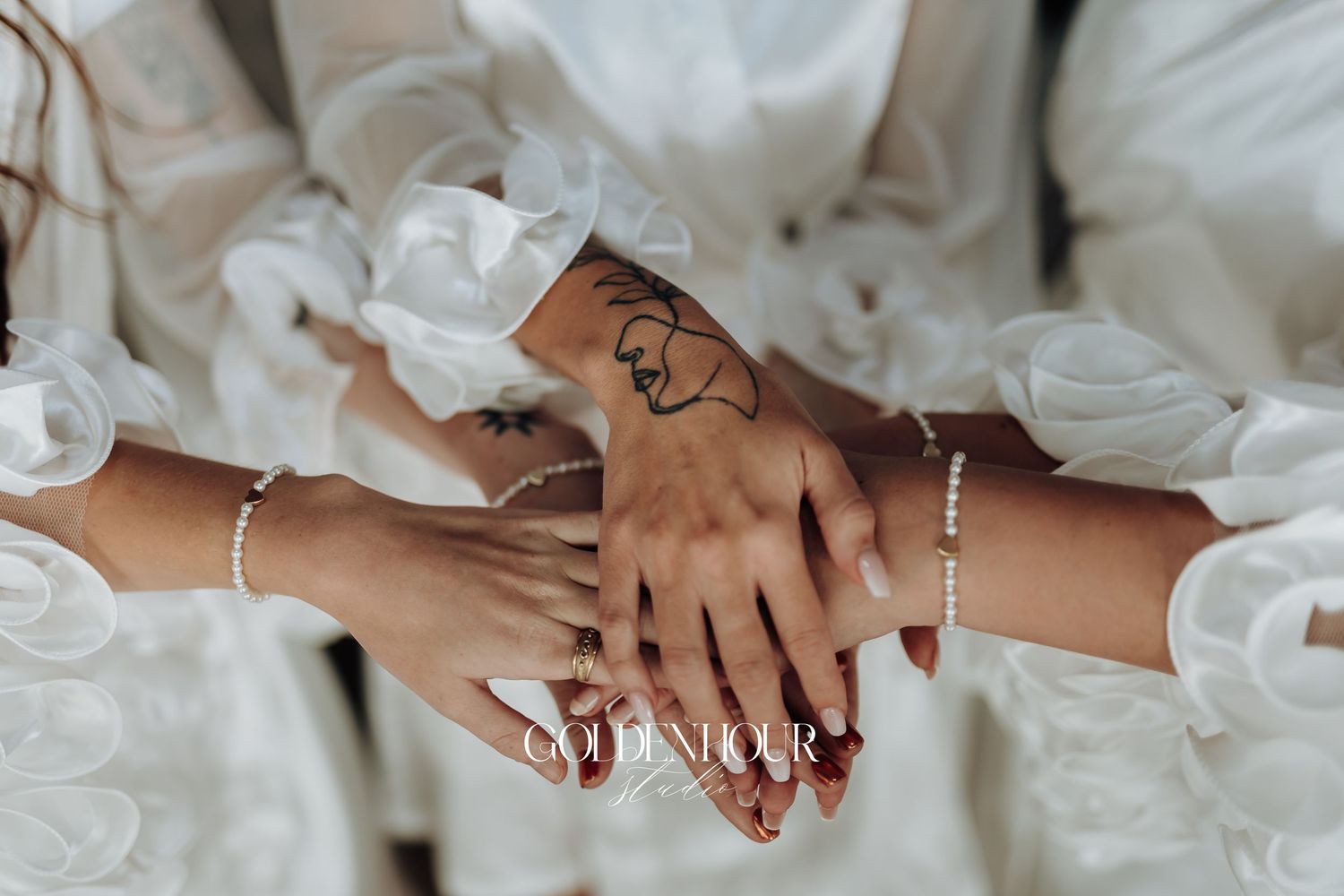 Close-up of hands with wedding rings and white attire details.