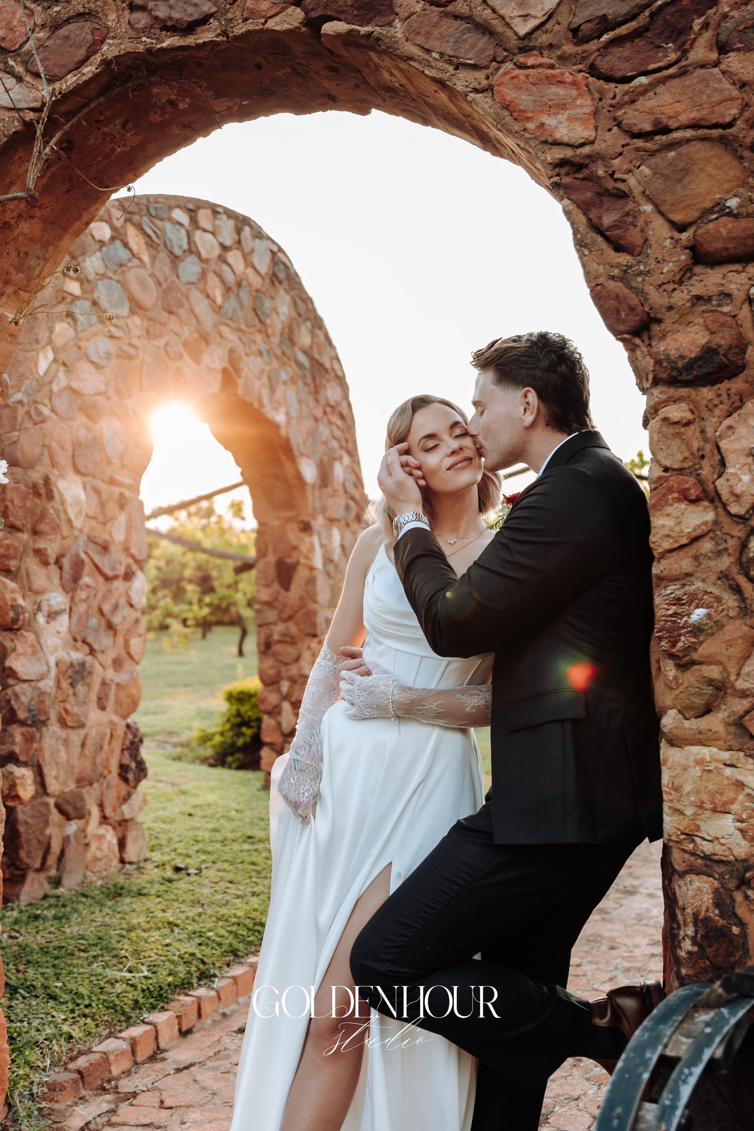 Romantic wedding photos captured under stone archways at golden hour.
