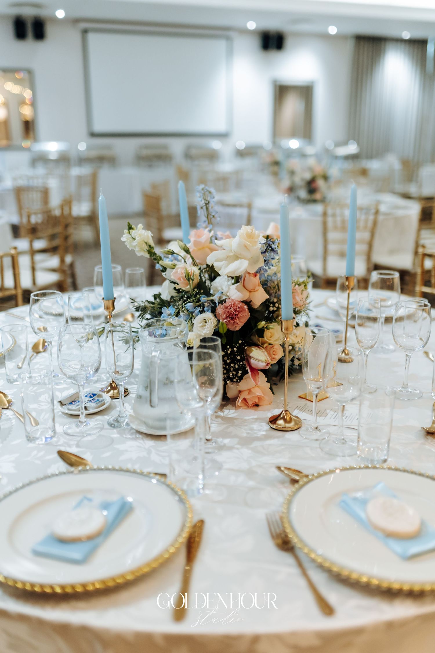 Elegant wedding reception table setting with floral centerpiece and gold accents.