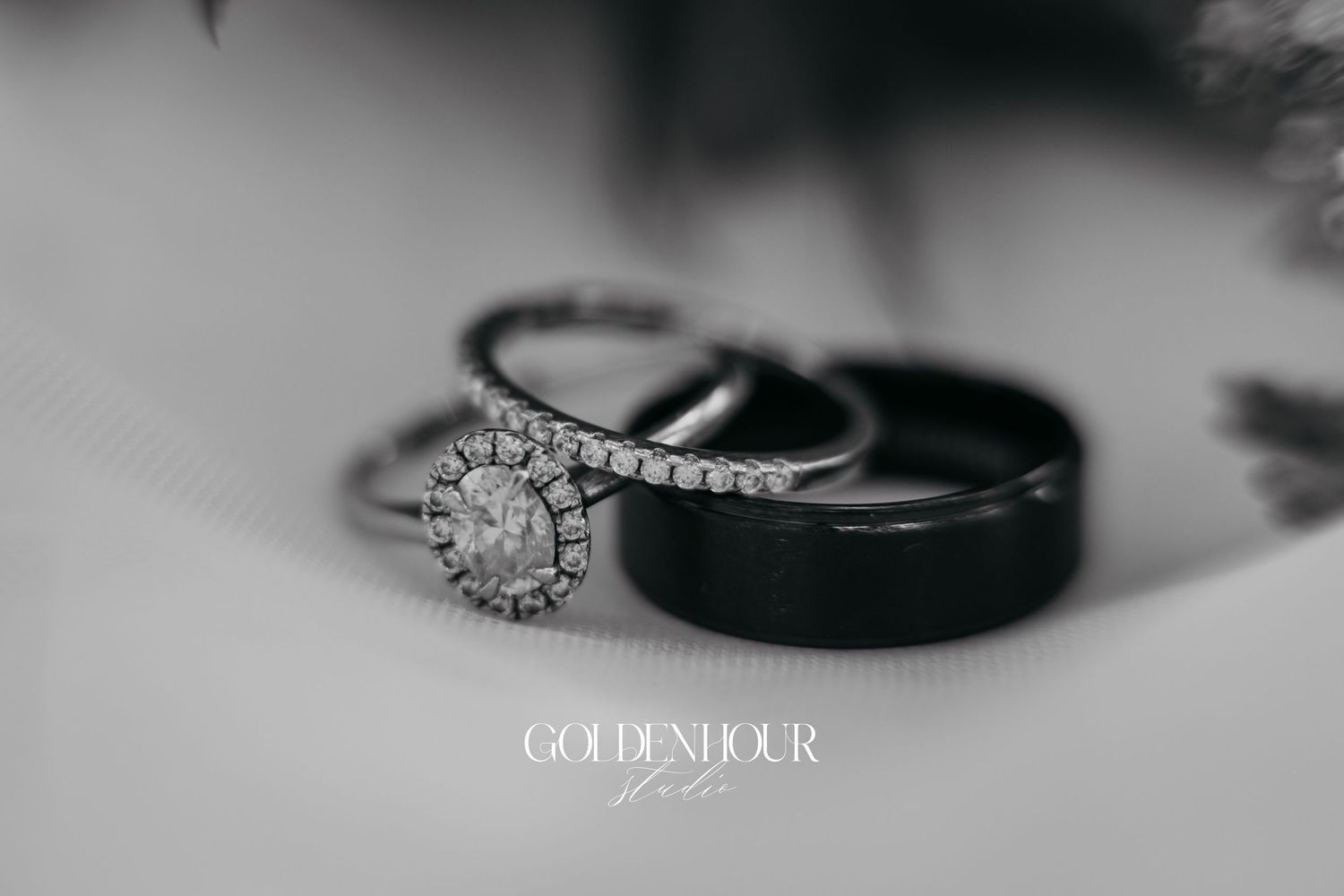 A collection of wedding rings and bands arranged in a row shown in black and white photography.