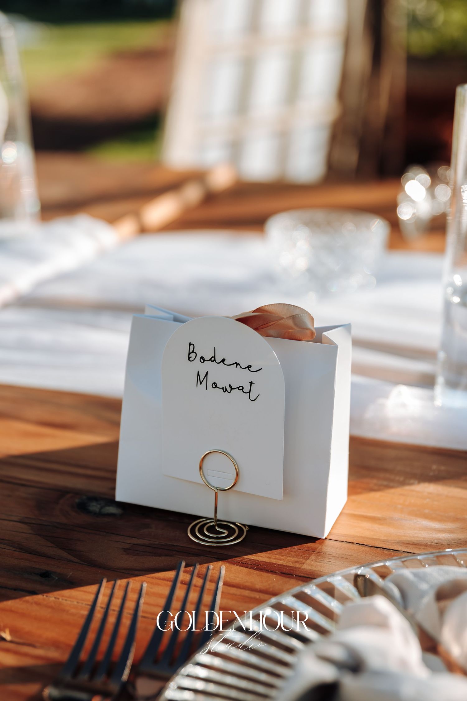 White place cards with elegant gold calligraphy sit on a wooden dining table at an upscale event setting.
