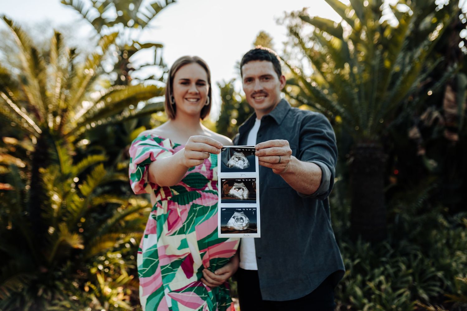 A series of outdoor photos showing a couple celebrating with ultrasound photos in a garden setting during golden hour.