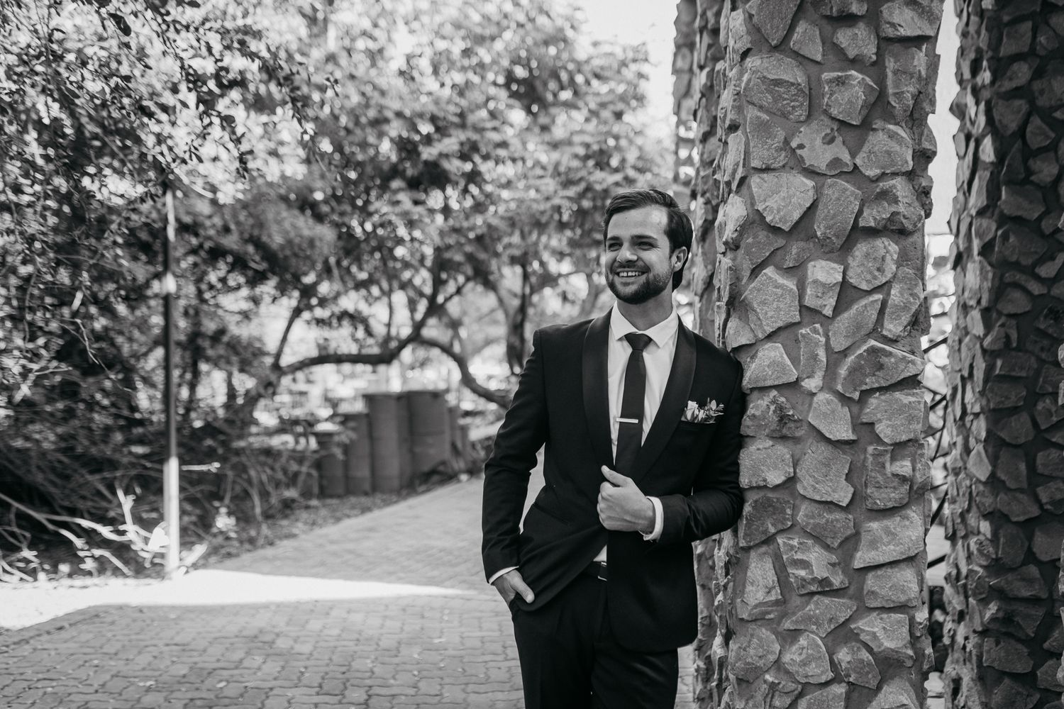 Classic black and white portrait against stone columns on garden pathway.