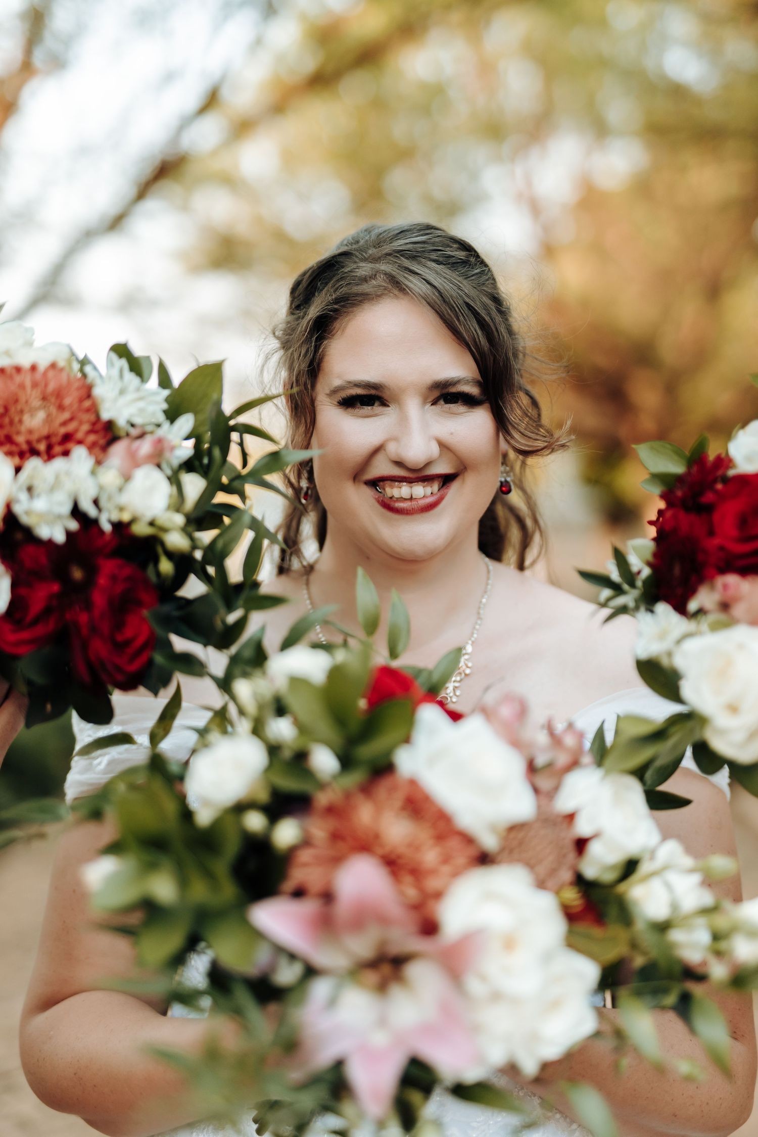 Beautiful wedding bouquet with red and white flowers against an autumn background.
