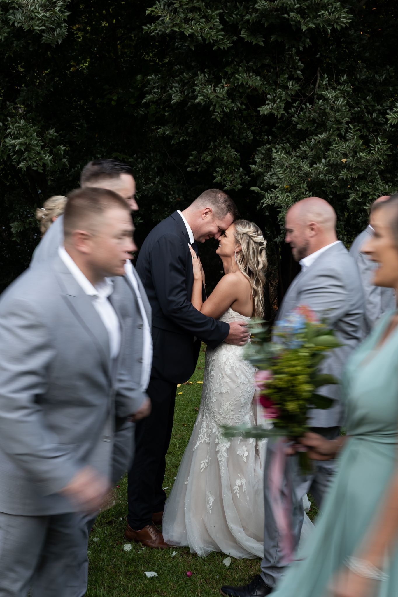 Candid moment during wedding celebration with party members in grey suits and mint dresses.