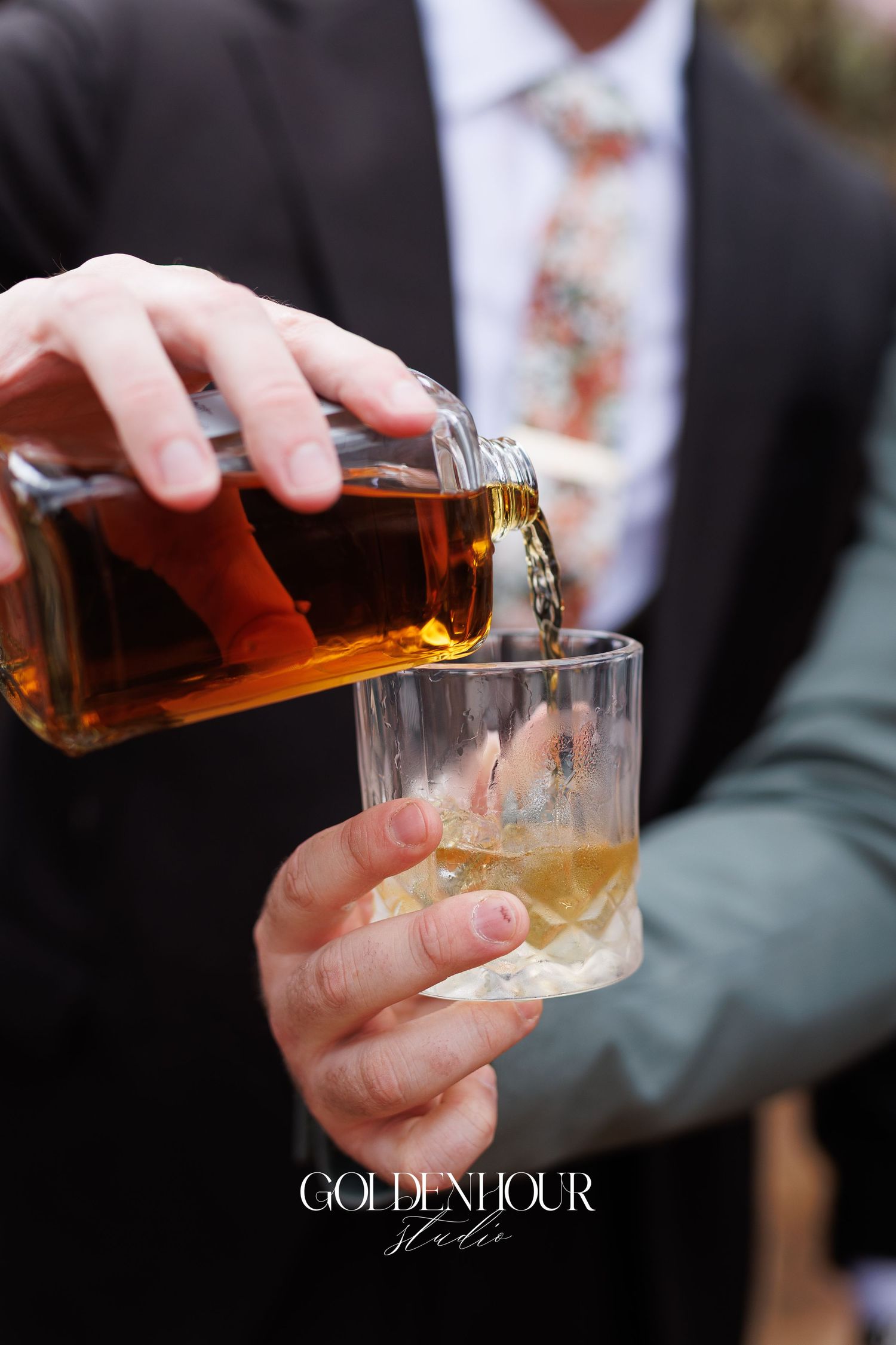 Whiskey being poured into a glass at a wedding reception with the Golden Hour logo overlay.