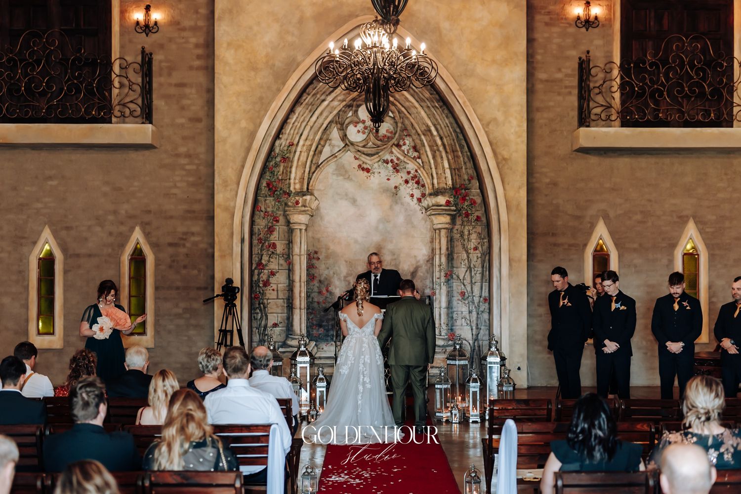 Wedding ceremony inside a stunning Gothic-style chapel with arched stone altar and guests seated.