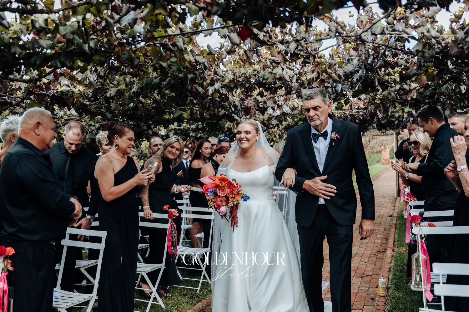 Wedding guests throw confetti at a joyful outdoor celebration under blooming trees.