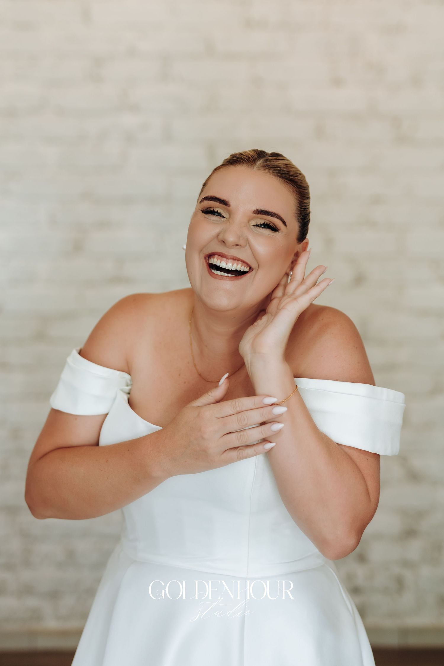 A joyful person wearing an elegant white off-shoulder dress poses and laughs in a series of candid photos.