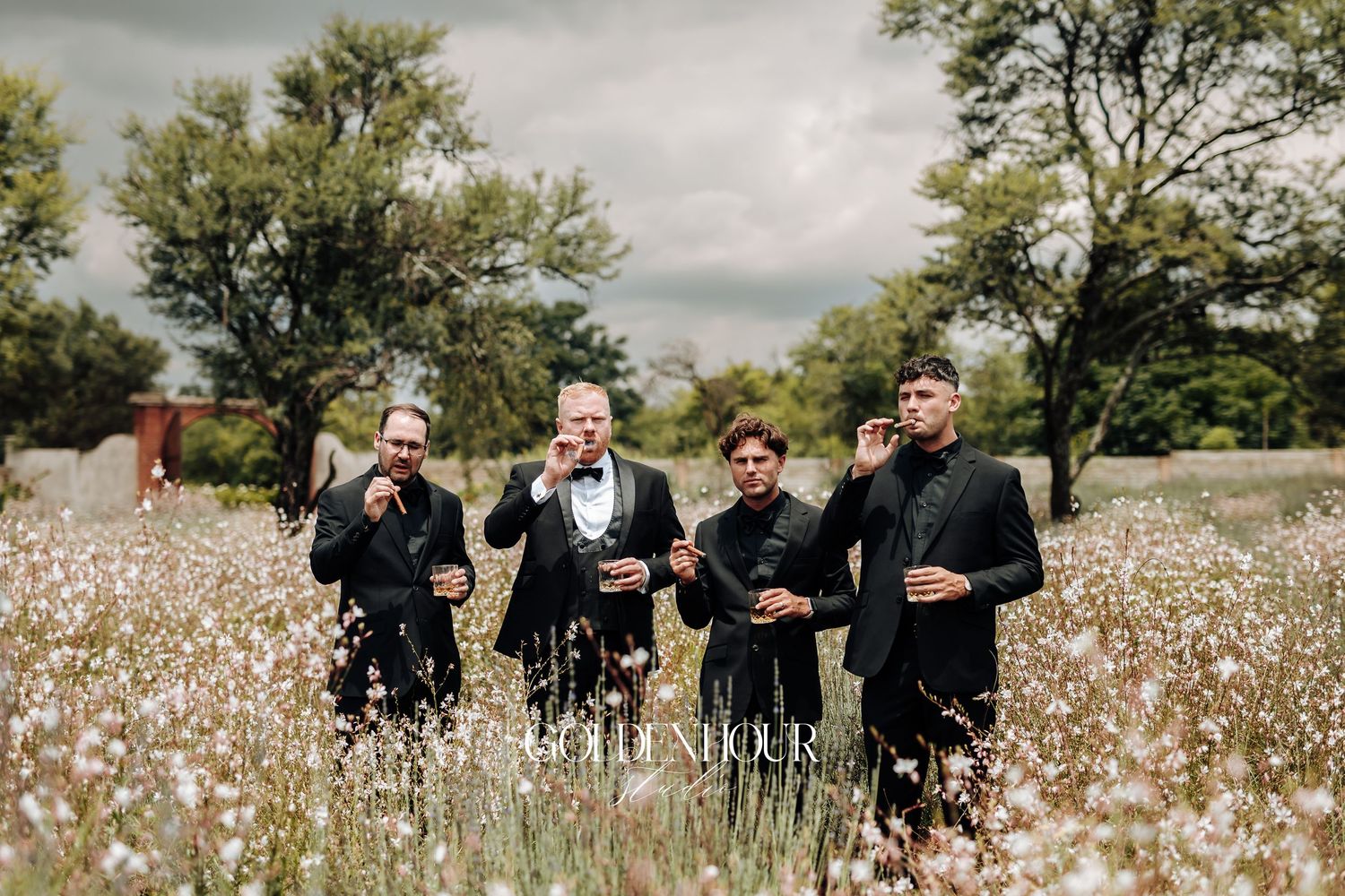 A group of people in formal attire standing together in a blooming cotton field on an overcast day.