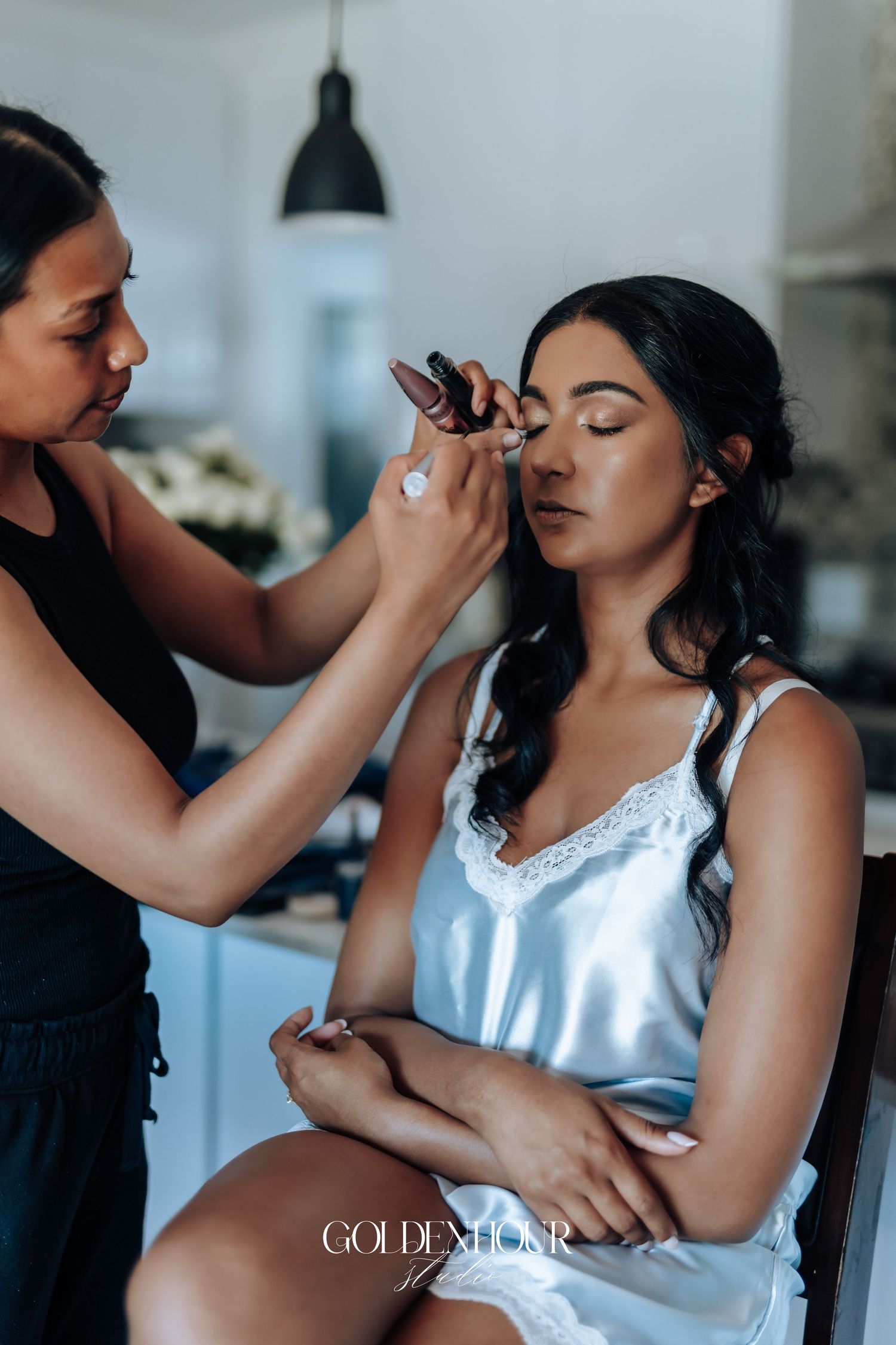 Makeup artist applying cosmetics to a bride during wedding day preparations.