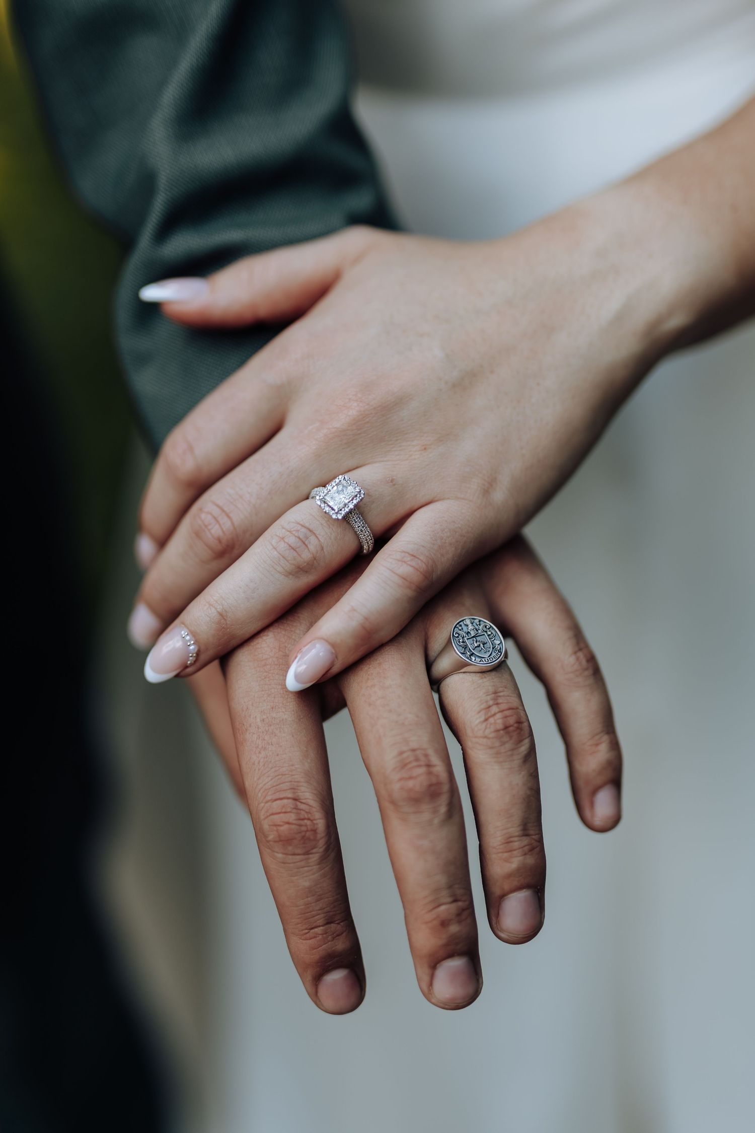 Close-up view of a sparkling engagement ring with a center diamond on a manicured hand.