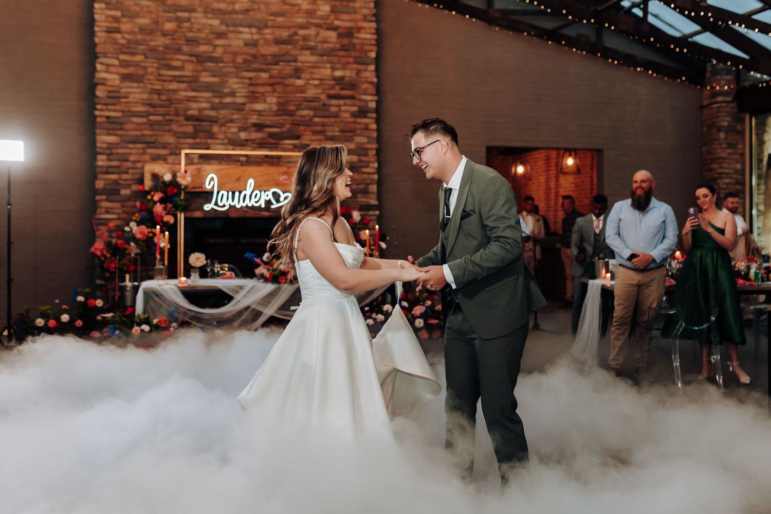 A couple dances in fog on their wedding day in a rustic brick venue.