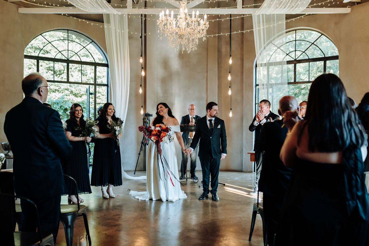 Elegant wedding venue interior with chandelier and arched windows.