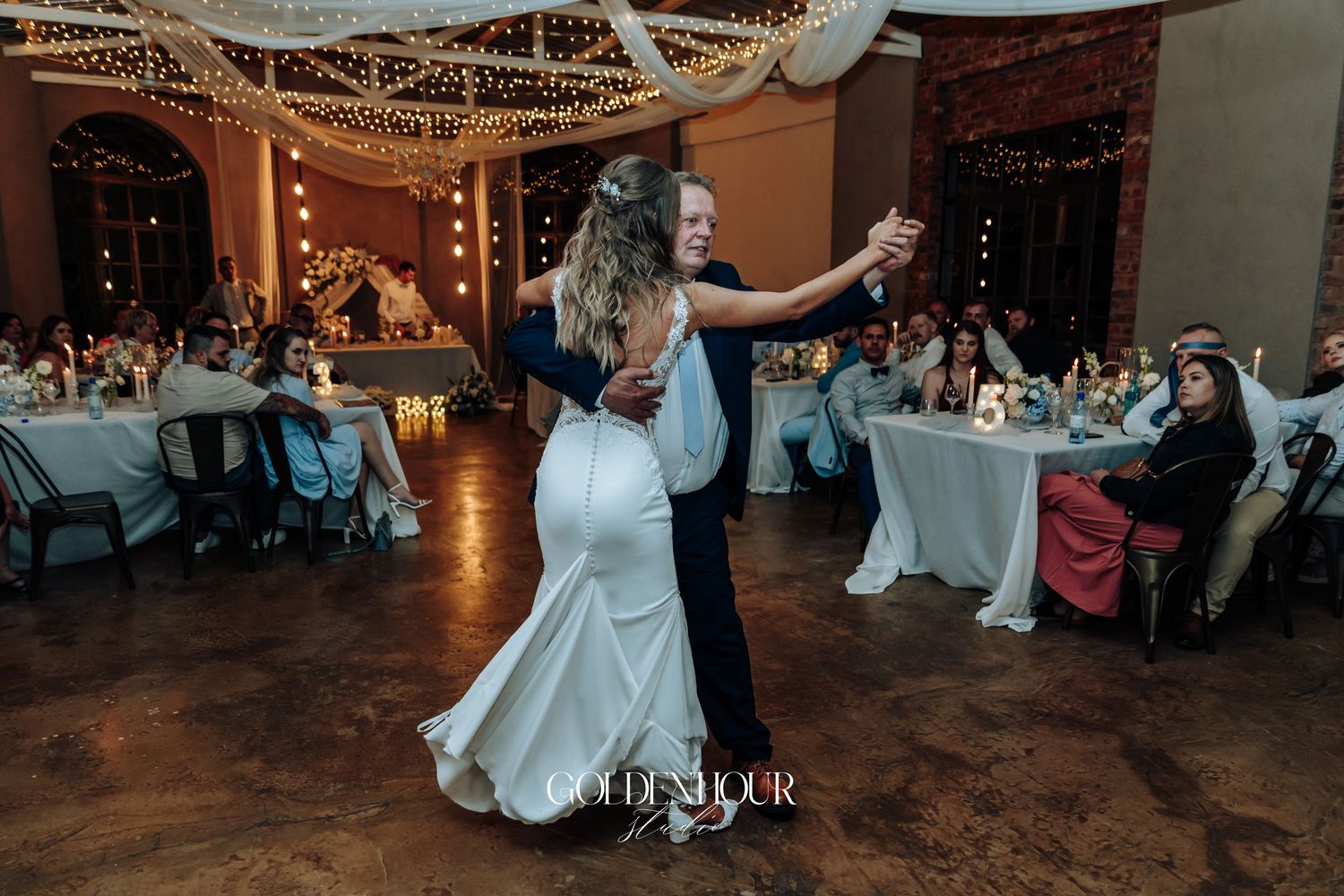 Wedding reception dance floor scene with string lights and romantic ambiance.