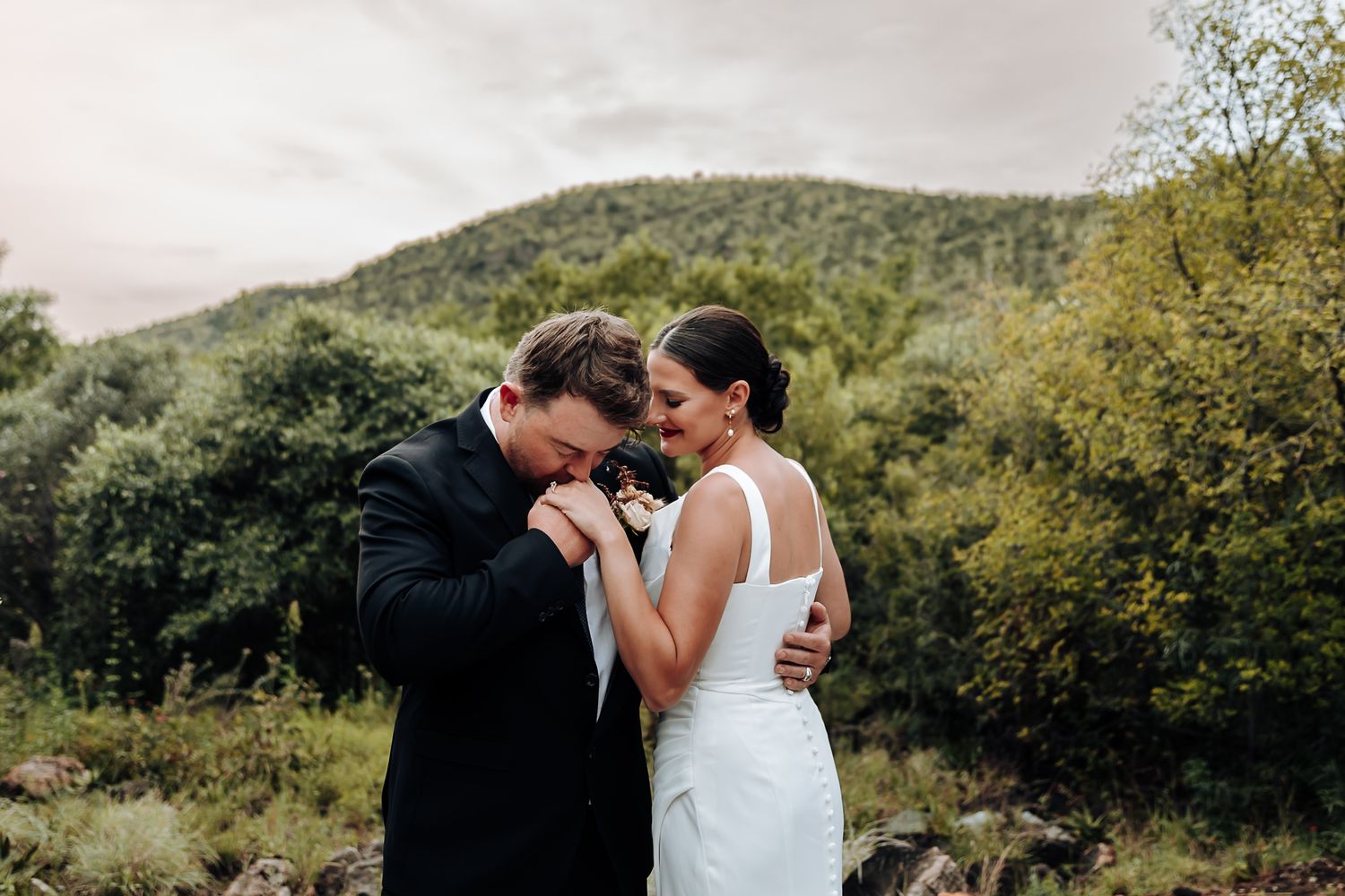 A romantic wedding photo series showing tender moments between a couple in a lush outdoor mountain setting.
