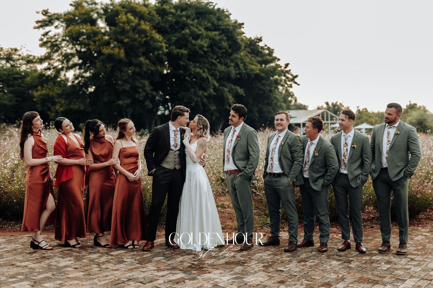 Large wedding party in burgundy and gray attire lined up for formal photo.