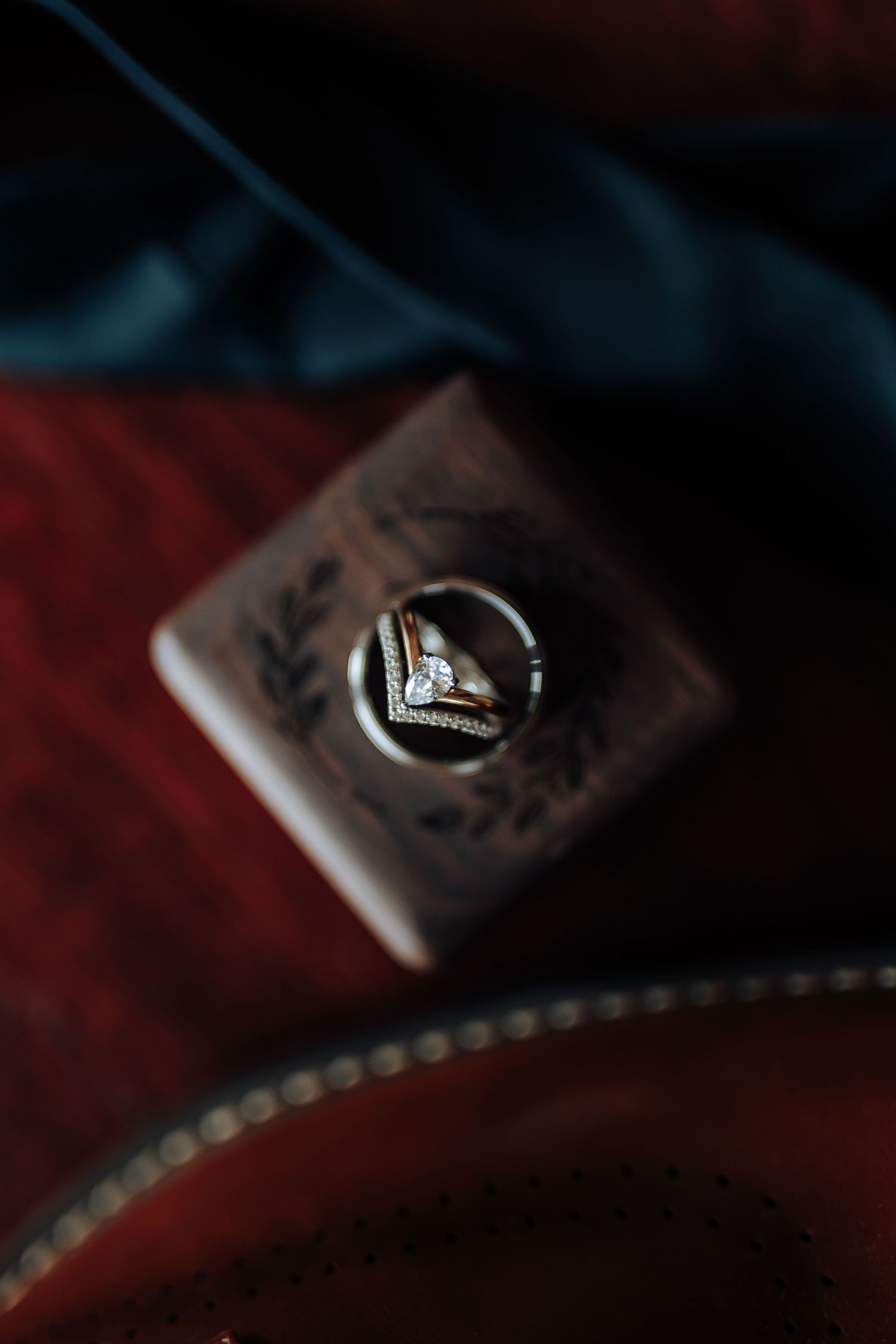 Close-up macro shot of a diamond engagement ring on a dark textured surface with dramatic lighting.