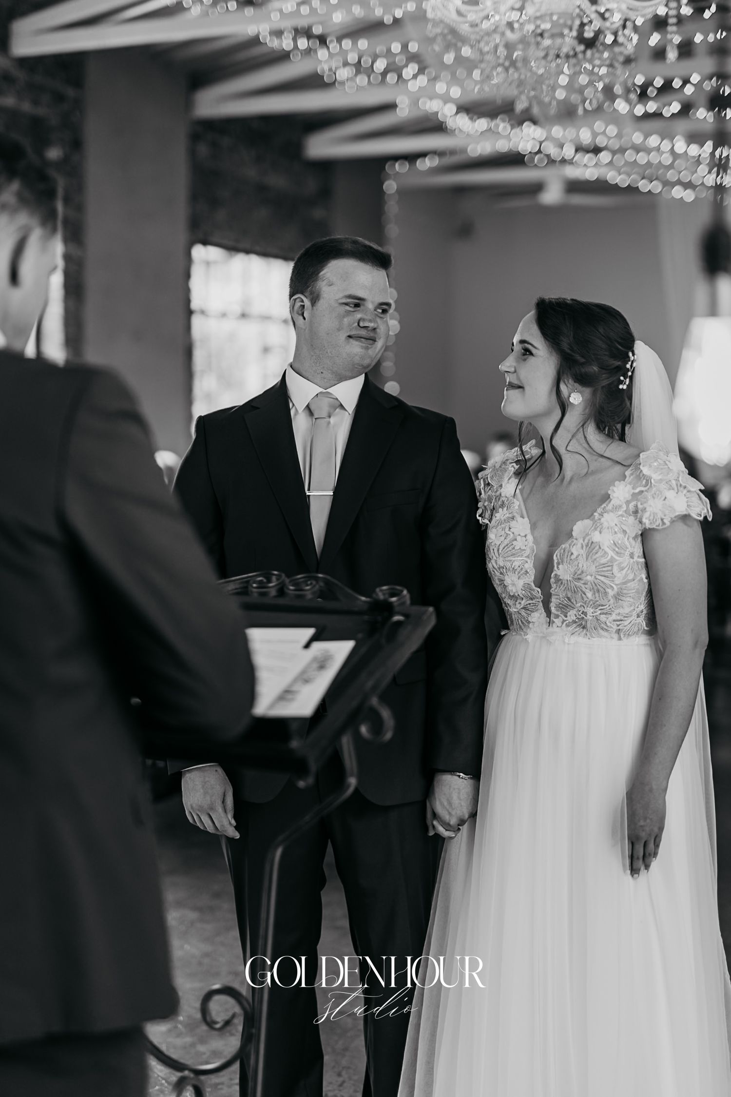 Black and white photo of bride and groom smiling during their wedding ceremony.
