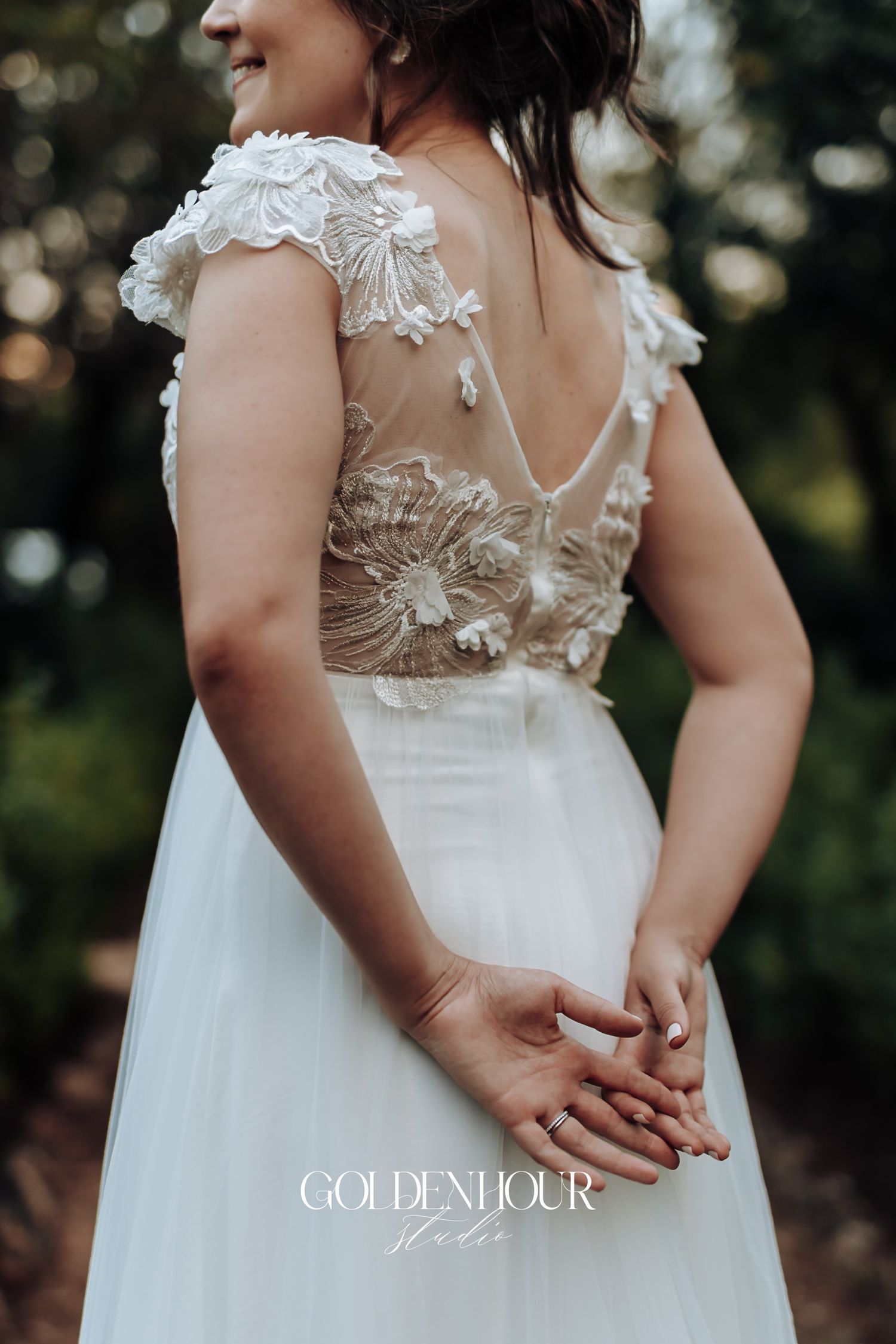 Close-up of intricate floral embroidery on the open back of a bride's white wedding gown.