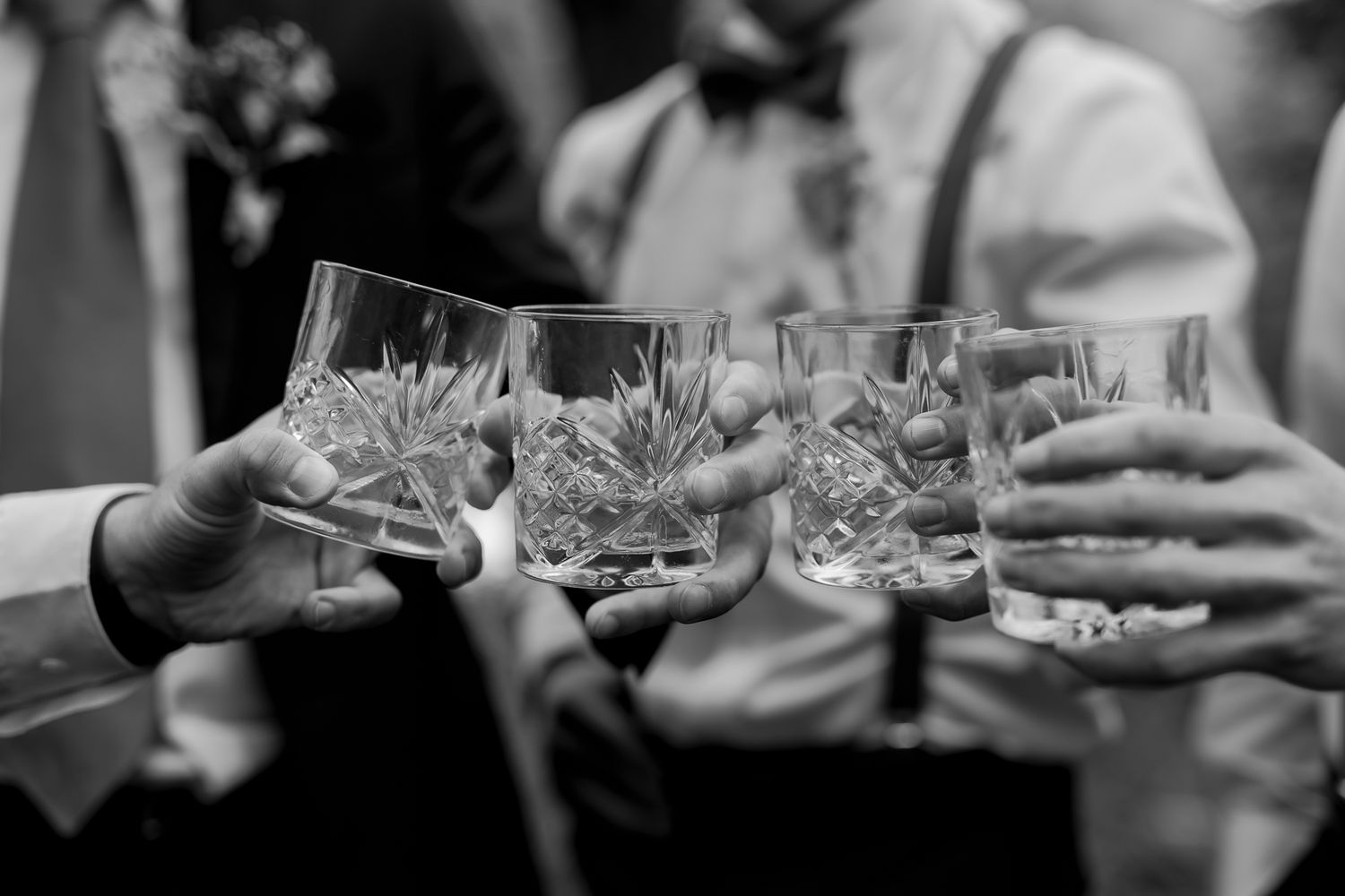 Black and white image of crystal glasses clinking in celebration.