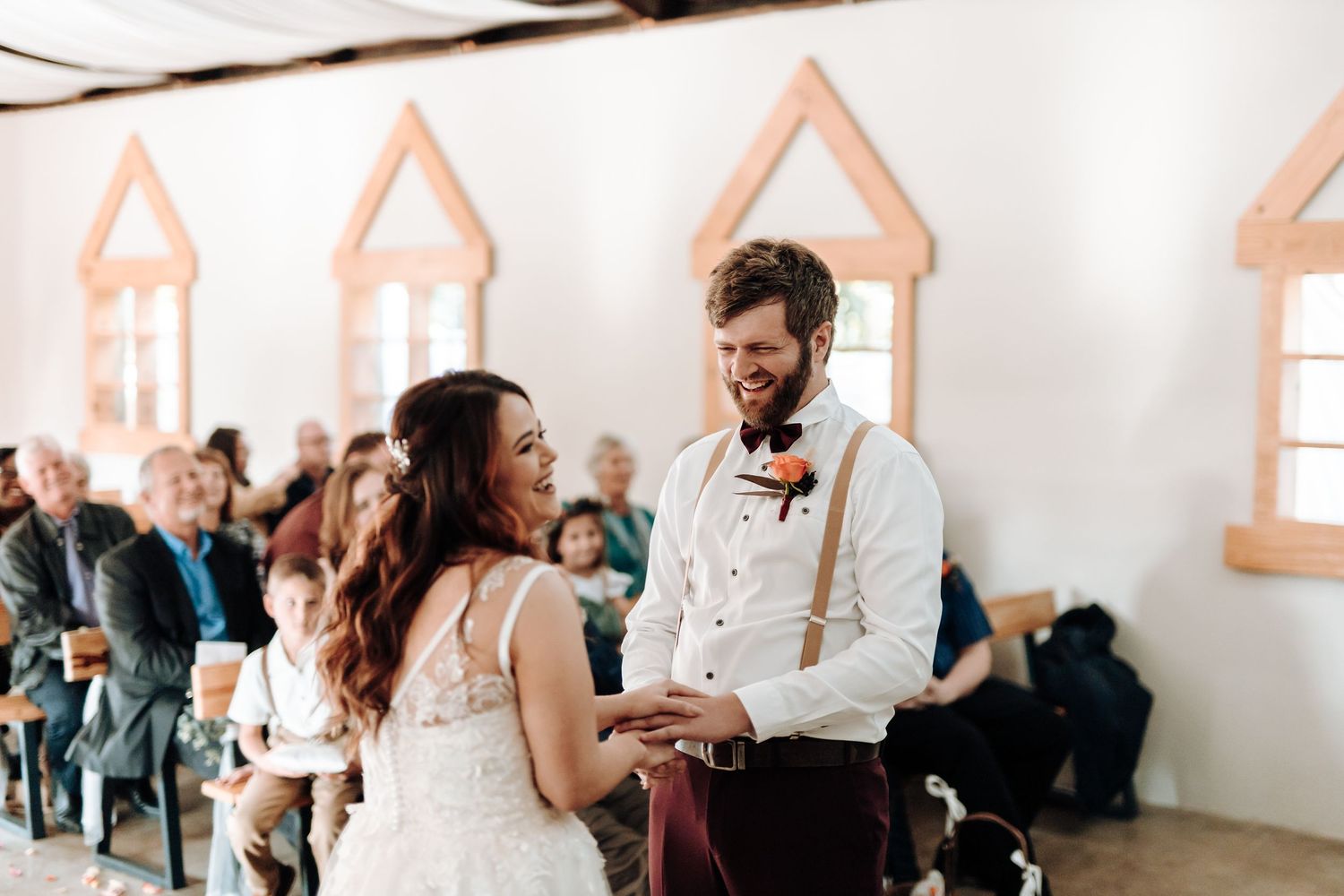 Wedding ceremony in progress inside a chapel with distinctive orange window details.