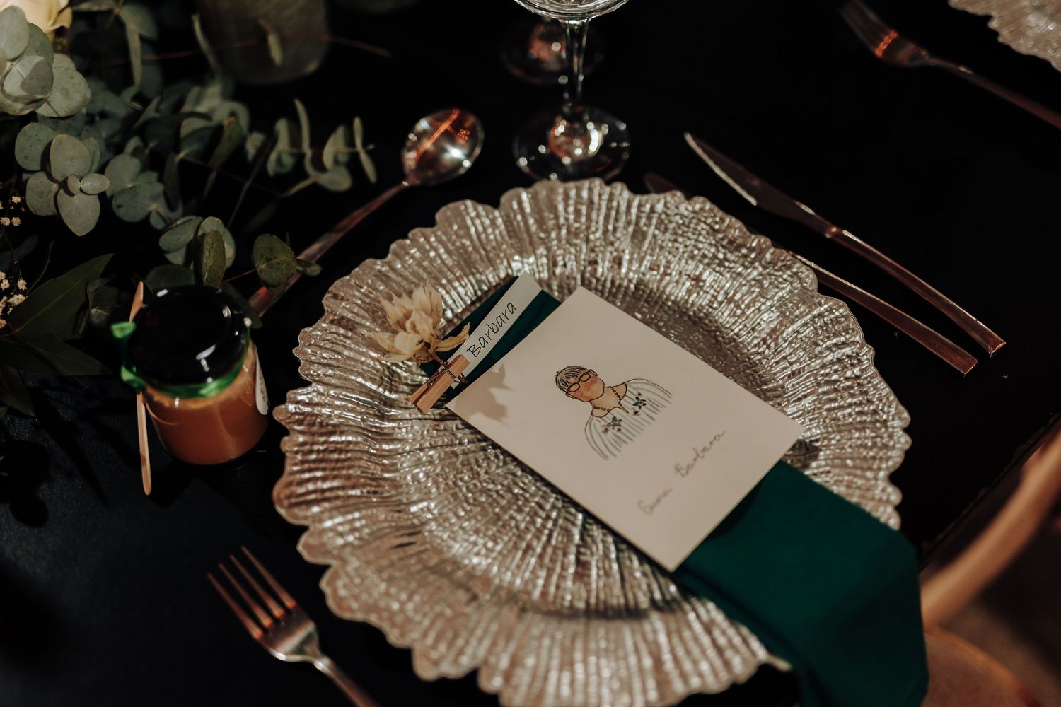 Detailed place setting with silver charger plate, green napkin, and menu card.