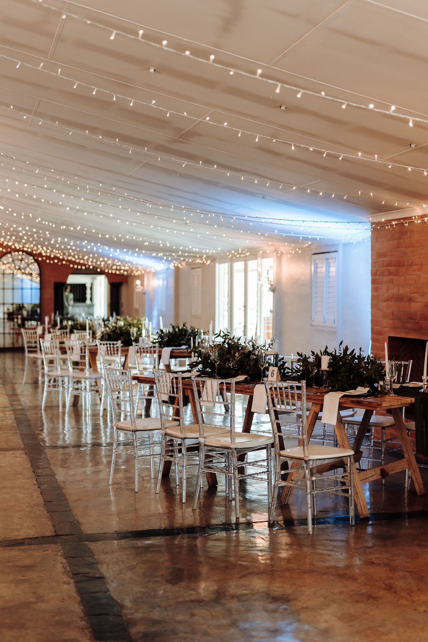Wedding reception venue with string lights and white chiavari chairs creating magical ambiance.