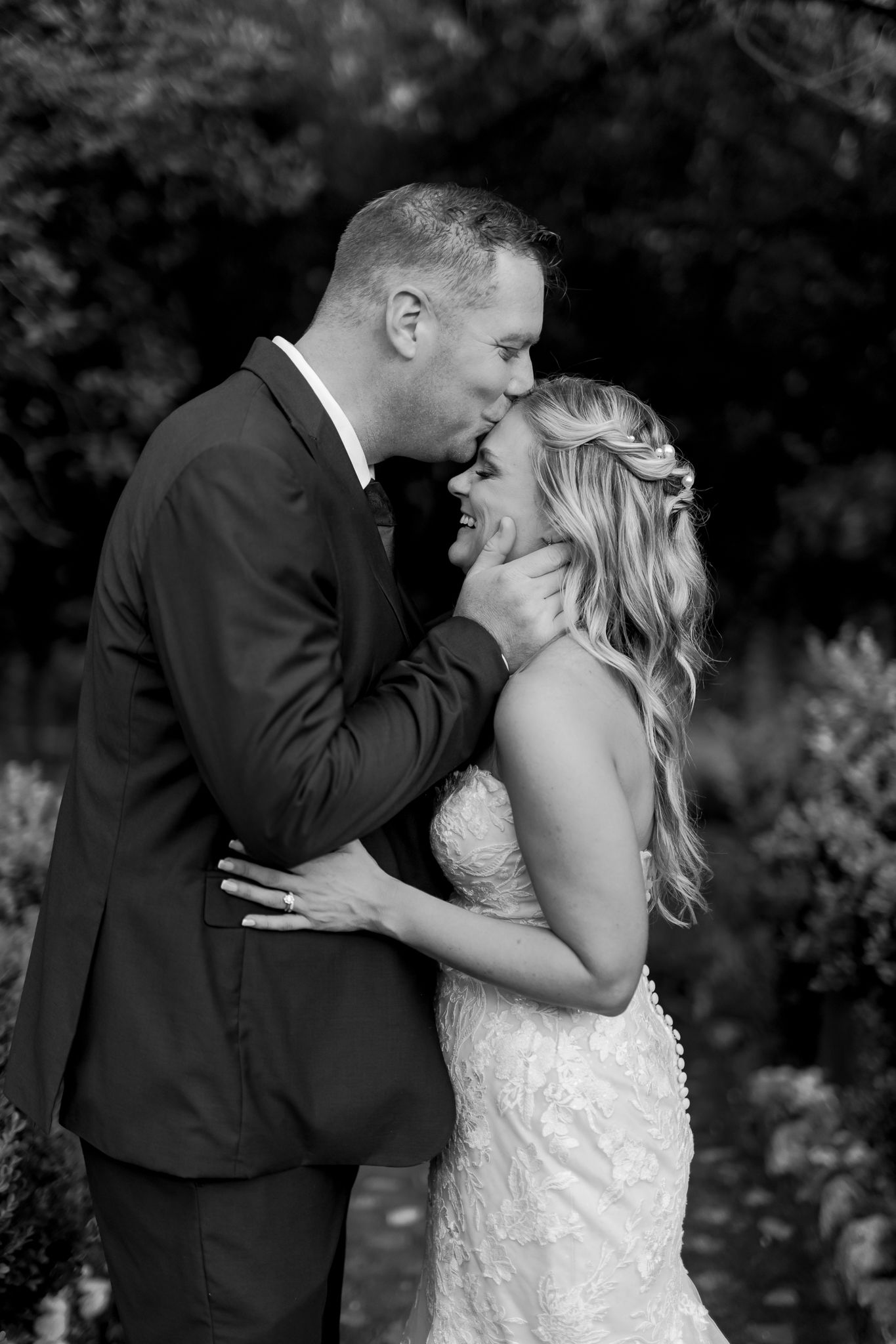 Black and white intimate wedding portrait in a natural outdoor setting.