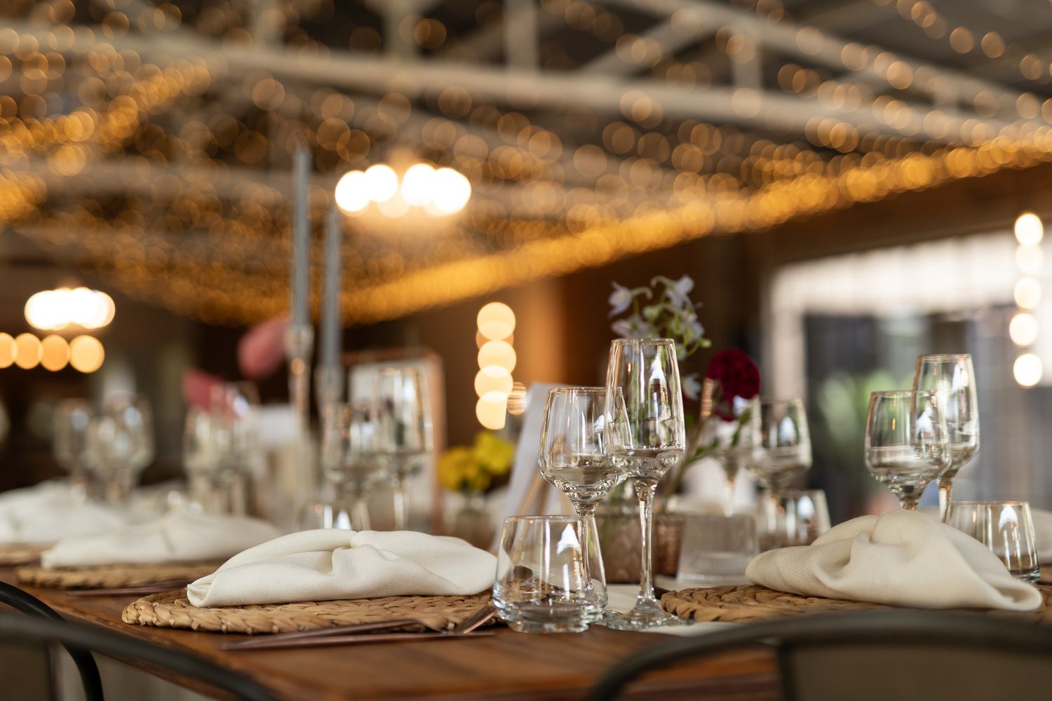 Elegant table settings with wine glasses and napkins under warm ambient lighting.