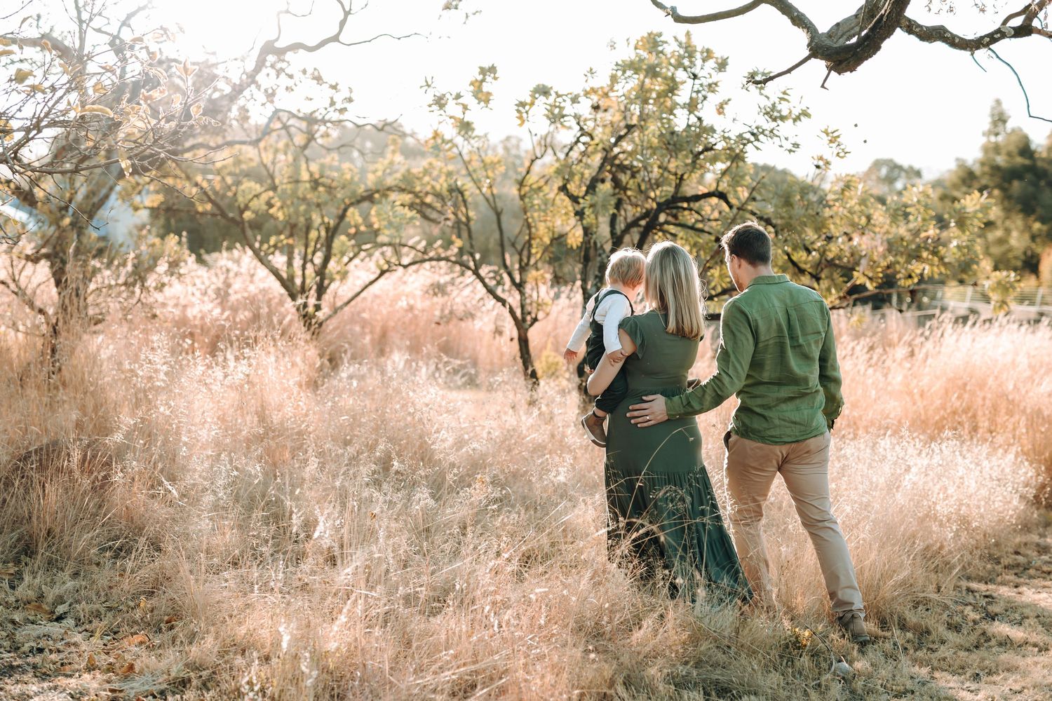 A couple shares an intimate moment while walking together through a golden autumn field at sunset.