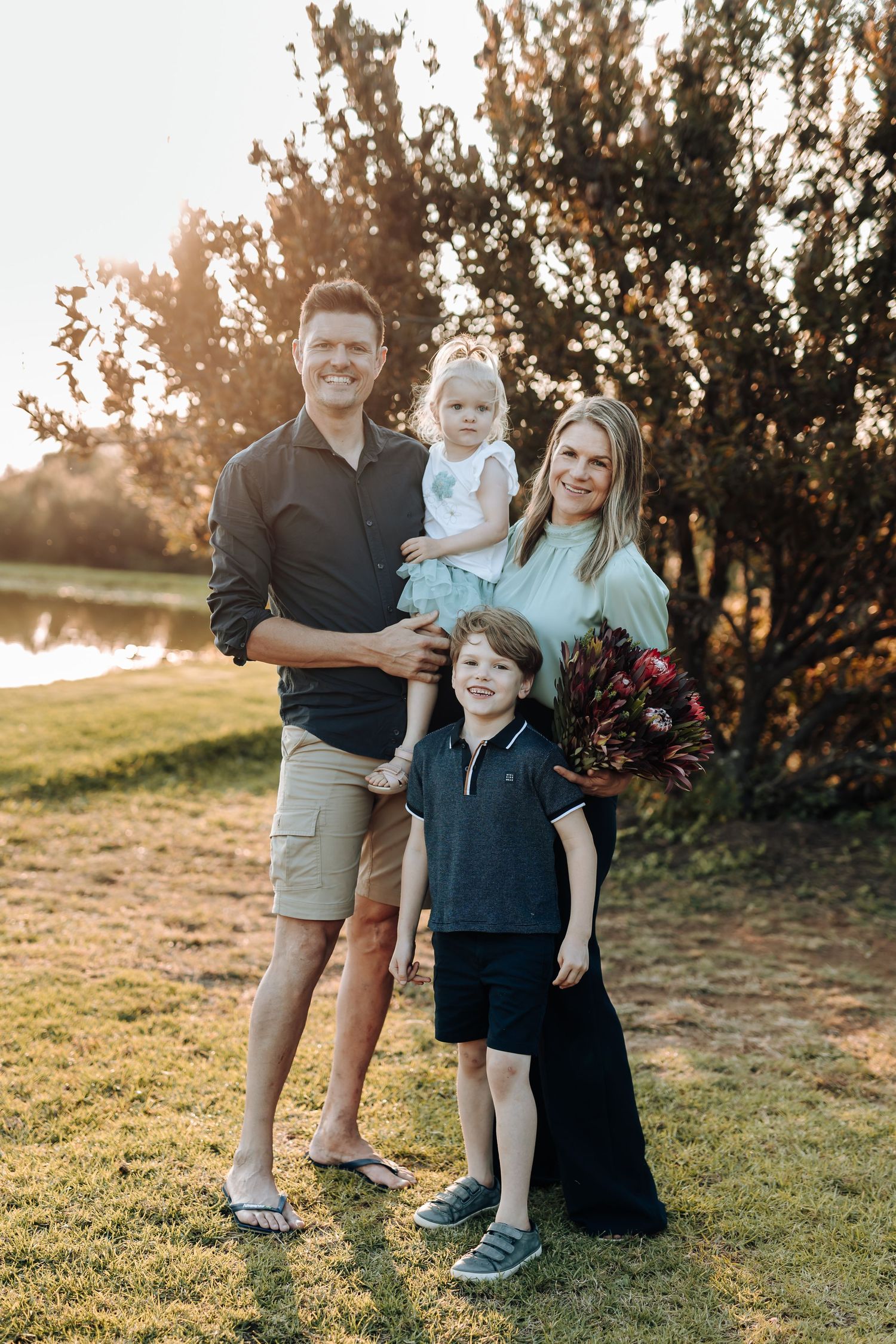 A family poses together on grassy terrain during golden hour sunset in a series of casual outdoor portraits.