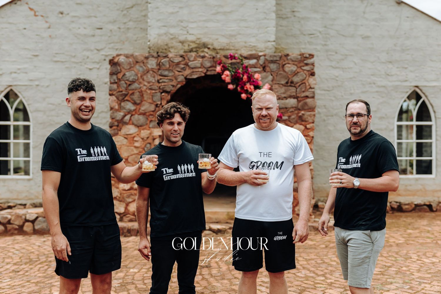 A group of people standing together outdoors against a stone building wall.