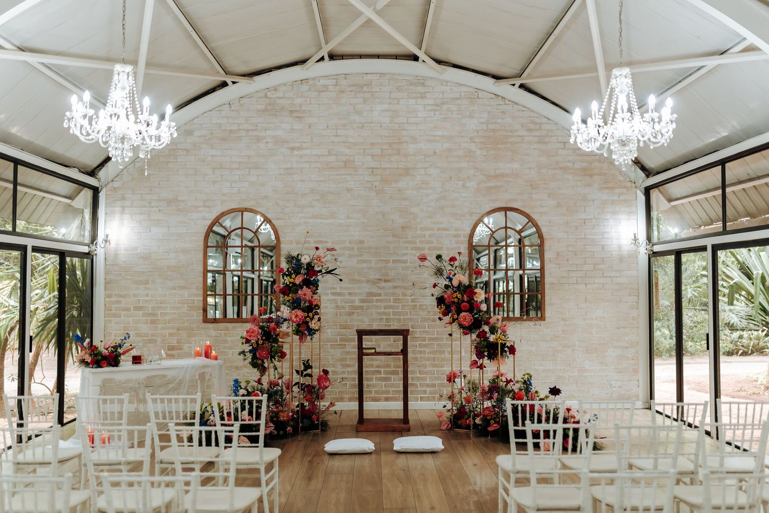 Elegant white chapel interior with crystal chandeliers, arched windows, and floral arrangements for a wedding ceremony.
