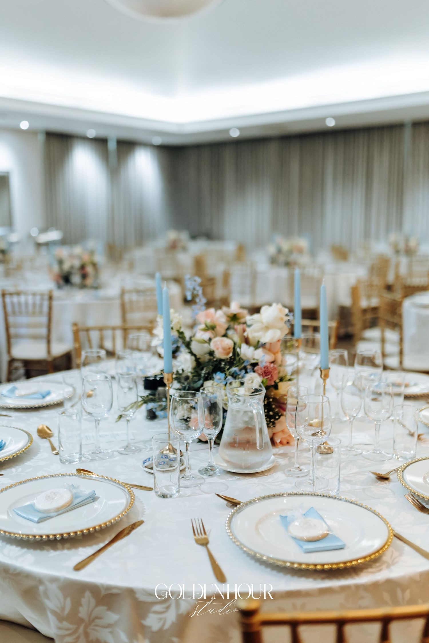 Elegant wedding reception table setting with gold chargers and floral centerpieces.