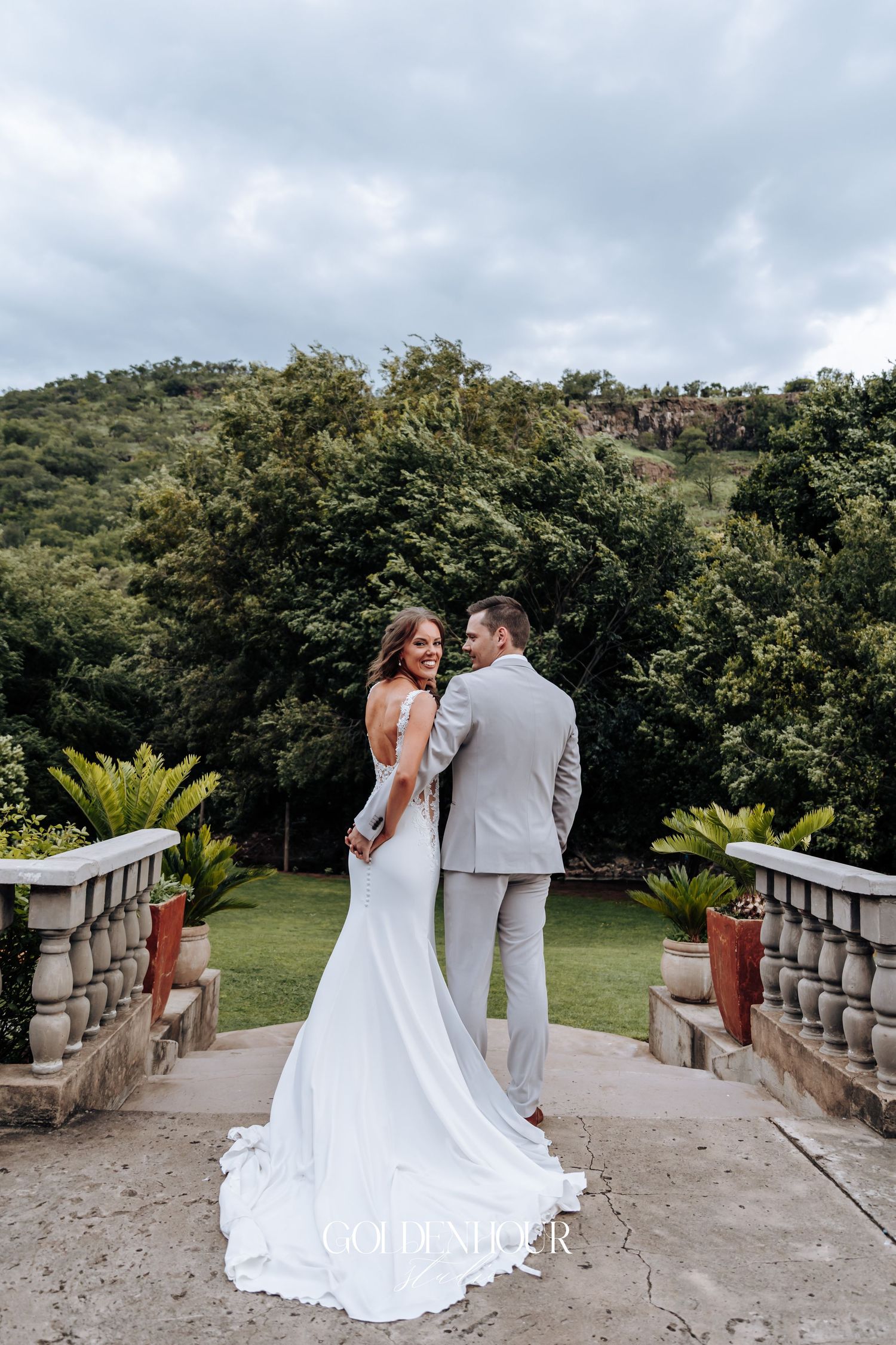 A romantic outdoor wedding portrait on a stone terrace with mountain views.