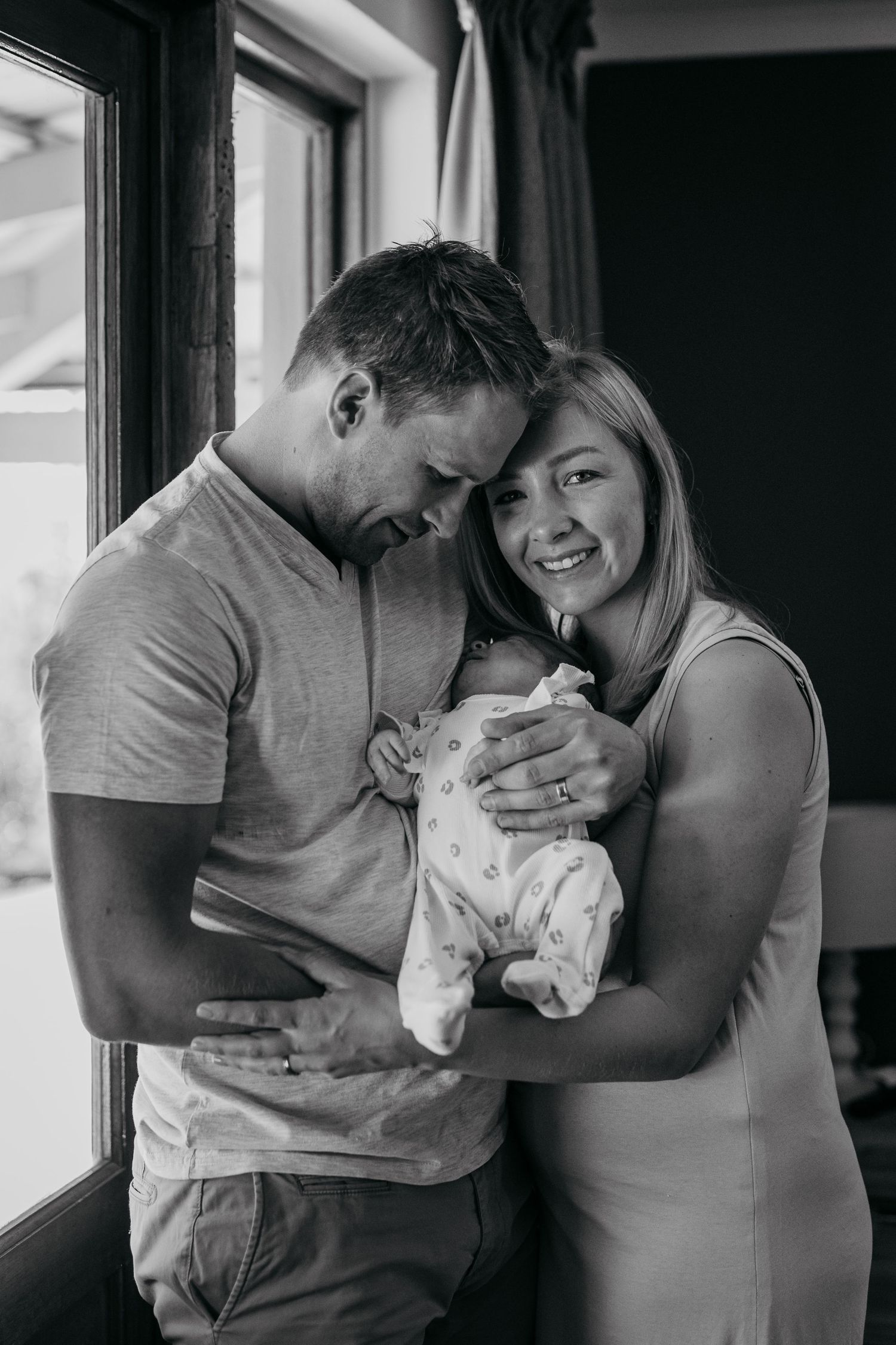 A couple shares intimate moments in black and white photographs while holding their small white dog.