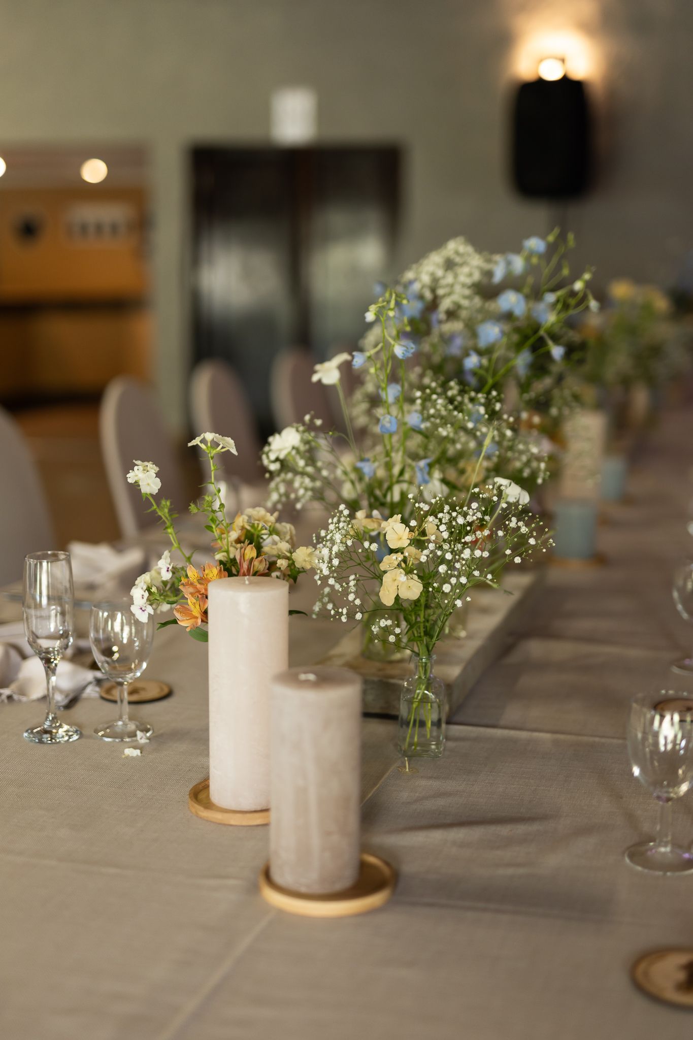 Wedding reception table with delicate floral arrangements and pillar candles on gold stands.