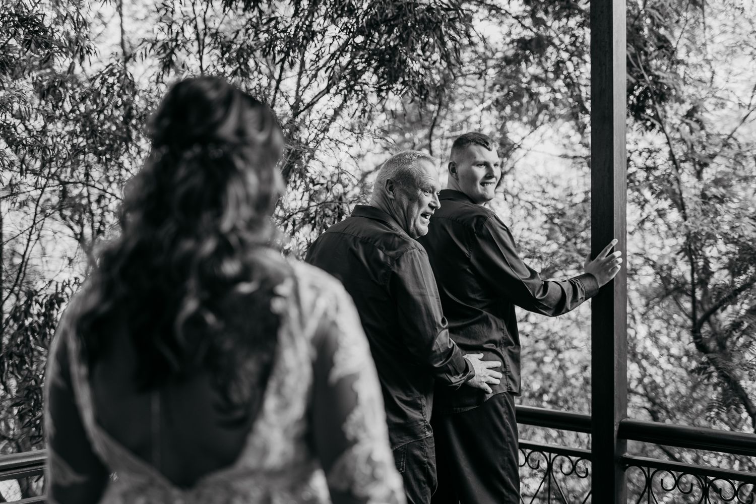 A black and white photo capturing candid wedding moments on an outdoor deck.