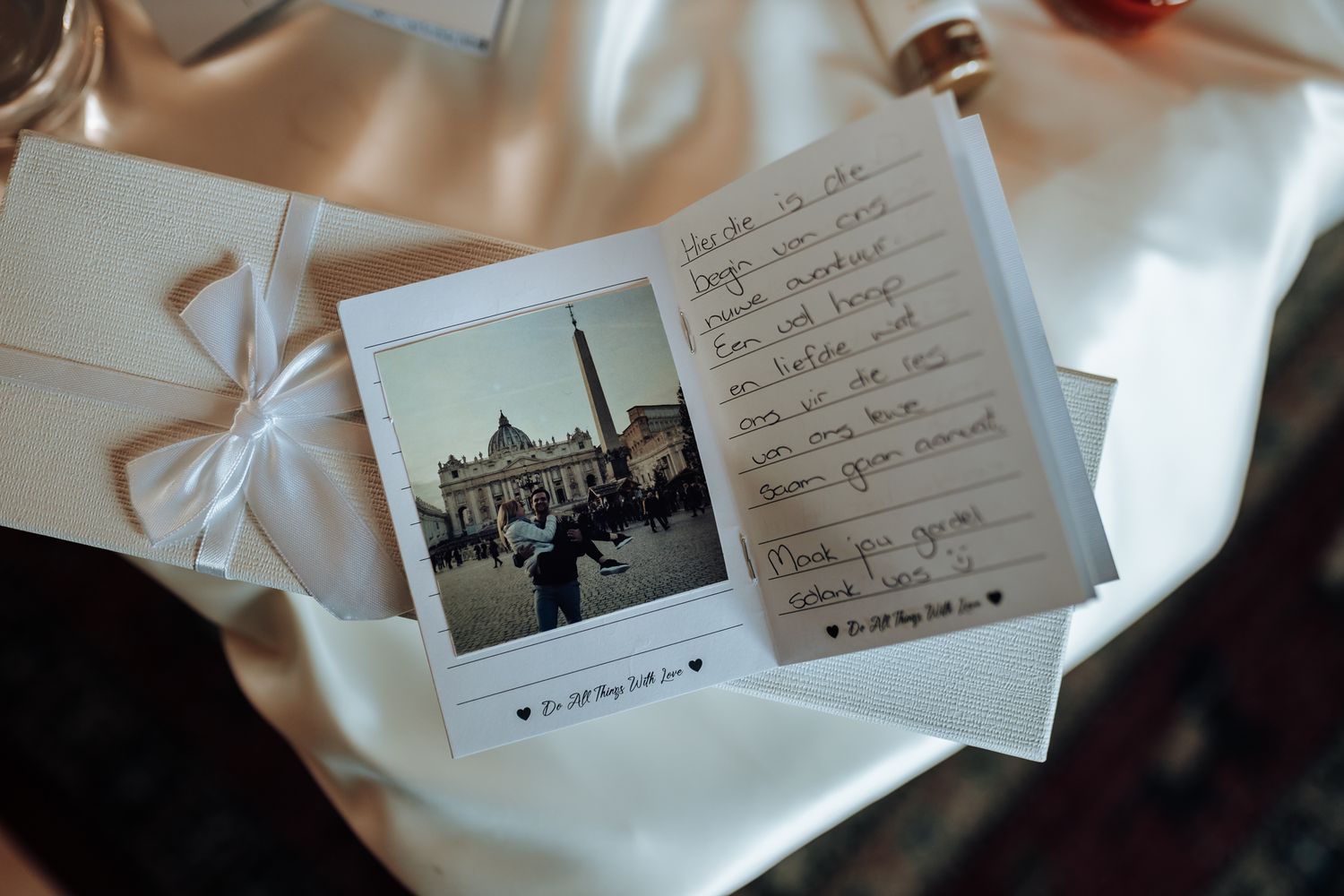A polaroid photo and handwritten note rest on smooth satin fabric.