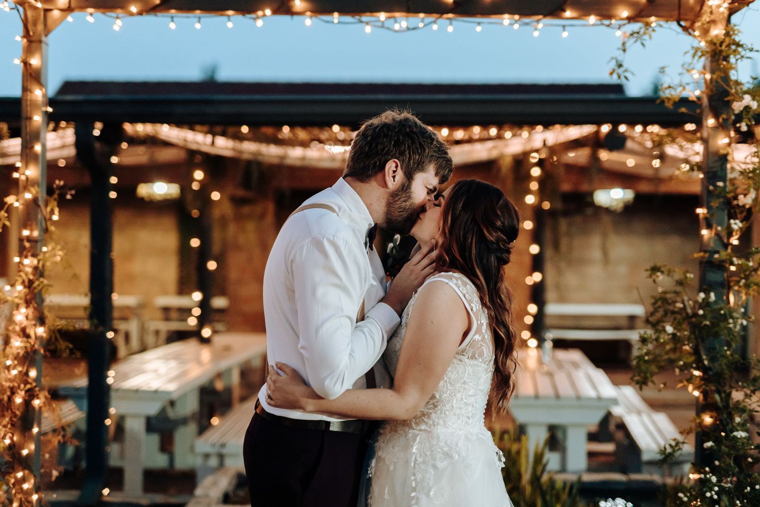 Evening wedding scene with string lights creating romantic ambiance under covered patio.