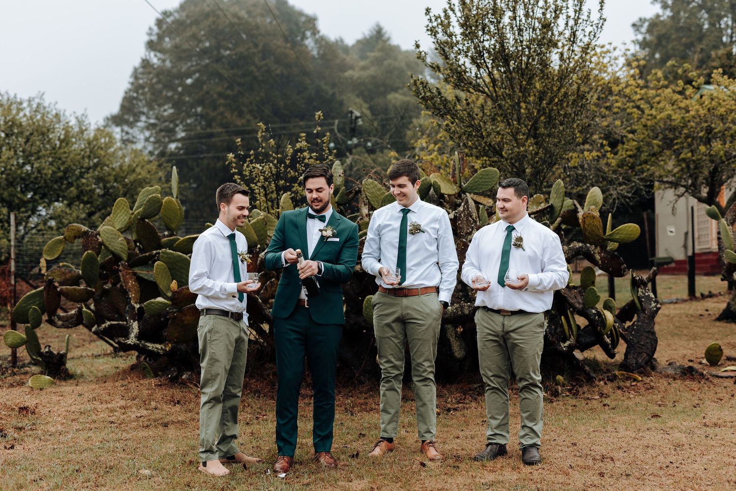 Group wearing coordinated formal attire standing in outdoor garden setting with cactus backdrop.
