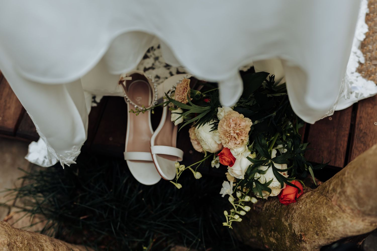 White and coral roses arranged with eucalyptus greenery and draped white fabric create an elegant wedding backdrop.