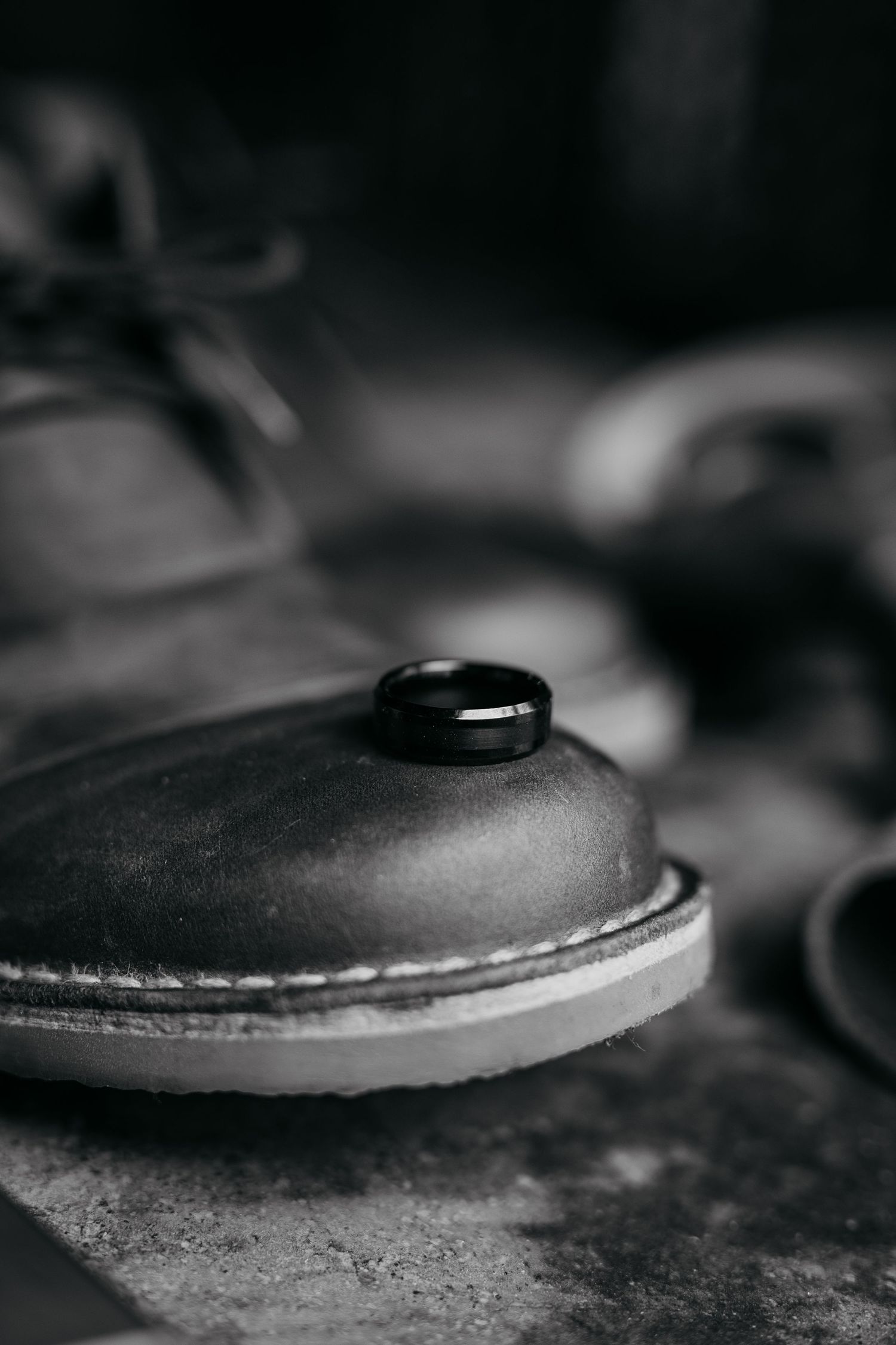 Close-up black and white macro photograph of a curved leather surface with textural details and stitching visible.