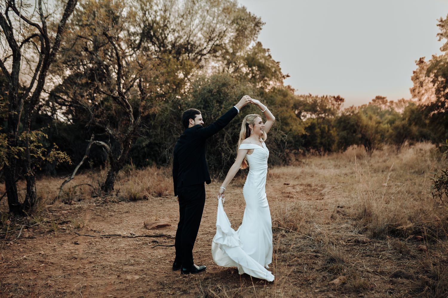 A couple performs an elegant dance pose against a natural backdrop.