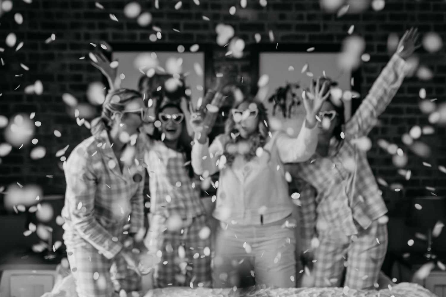 Group celebrates with confetti while wearing matching light-colored sleepwear.