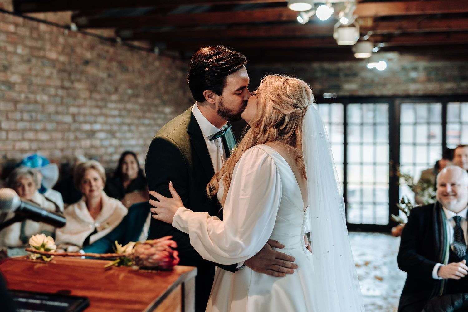 Romantic embrace between newlyweds during their reception in a rustic indoor venue.