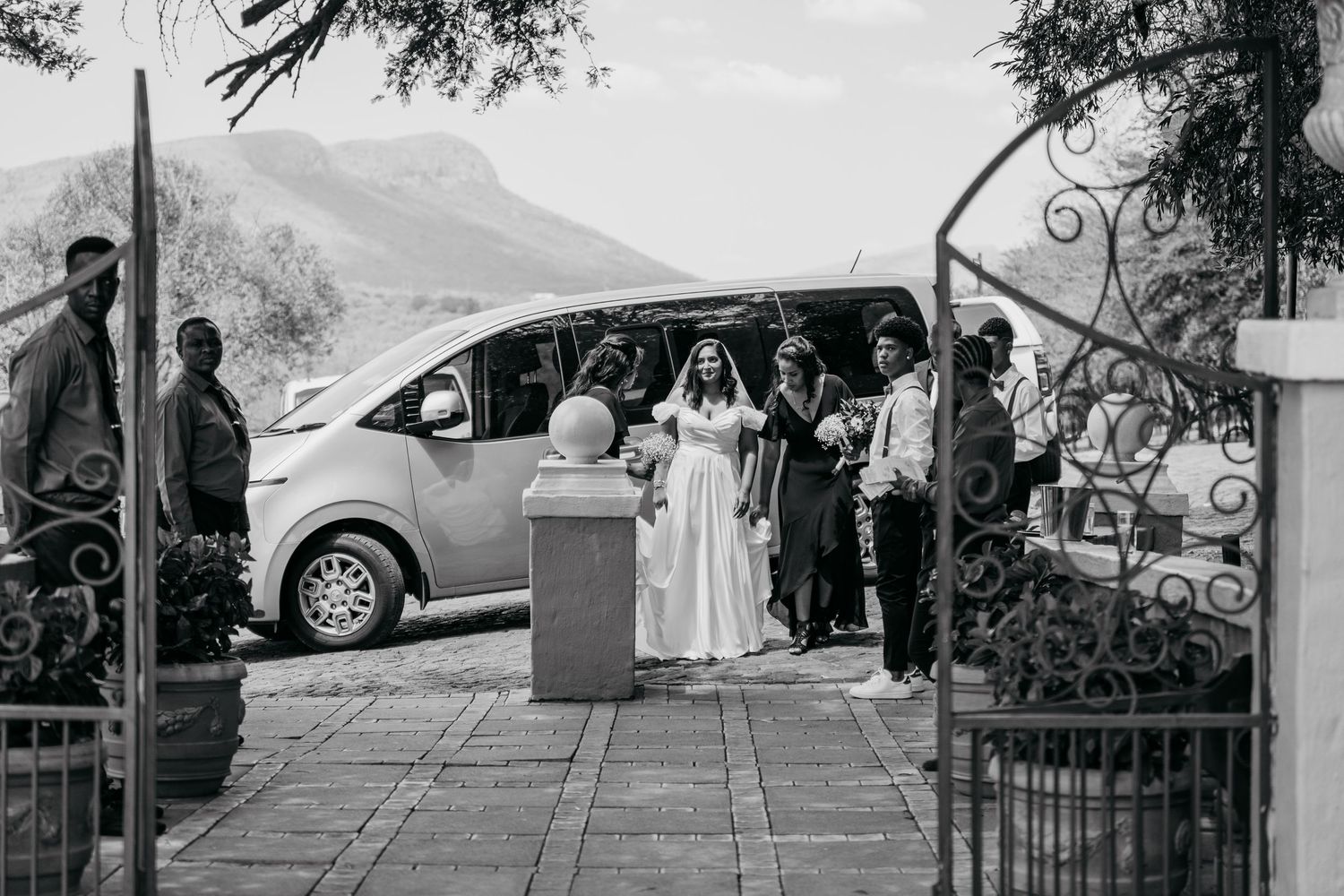 Black and white wedding photo showing group gathered at entrance gate.